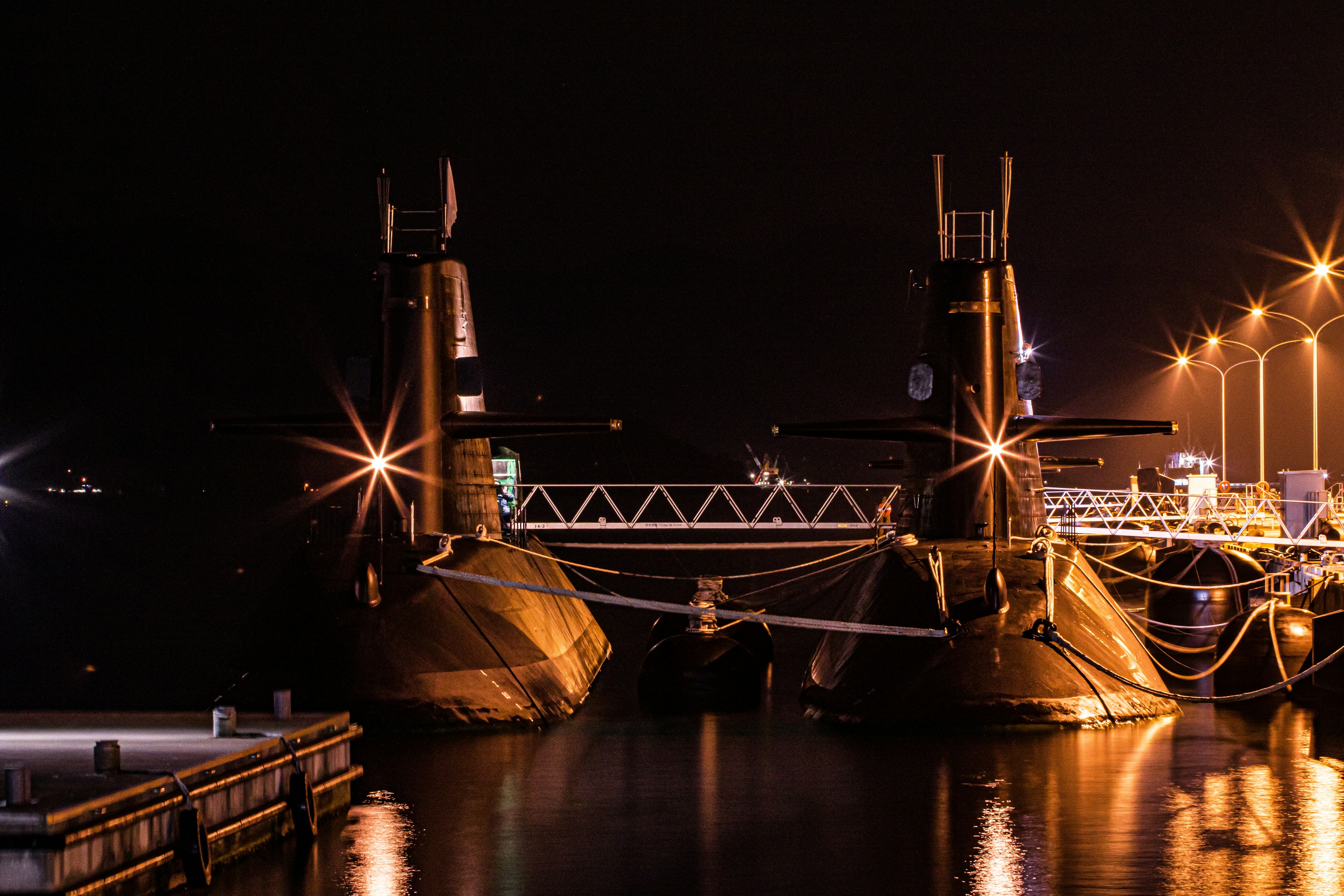 Vista nocturna de un puerto con estructuras de amarre iluminadas y barcos