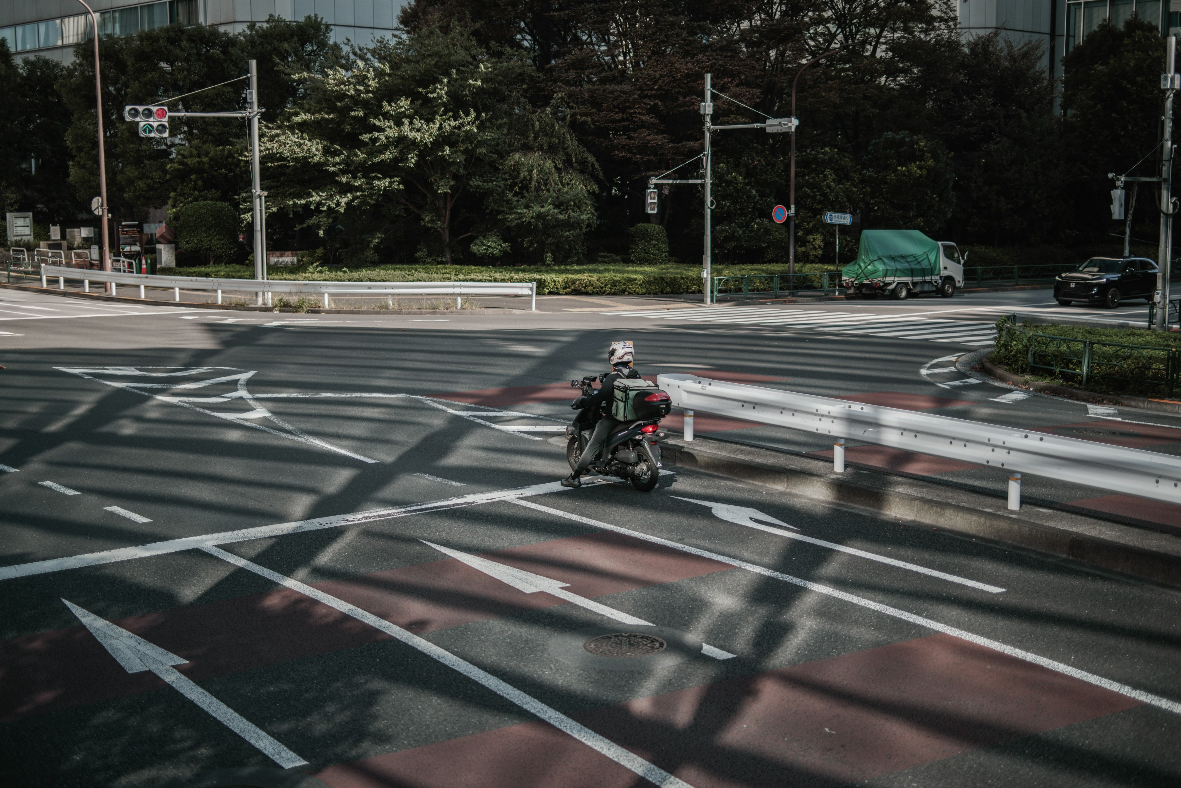 Lieferfahrer auf einem Motorrad an einer Kreuzung mit Schattenmustern