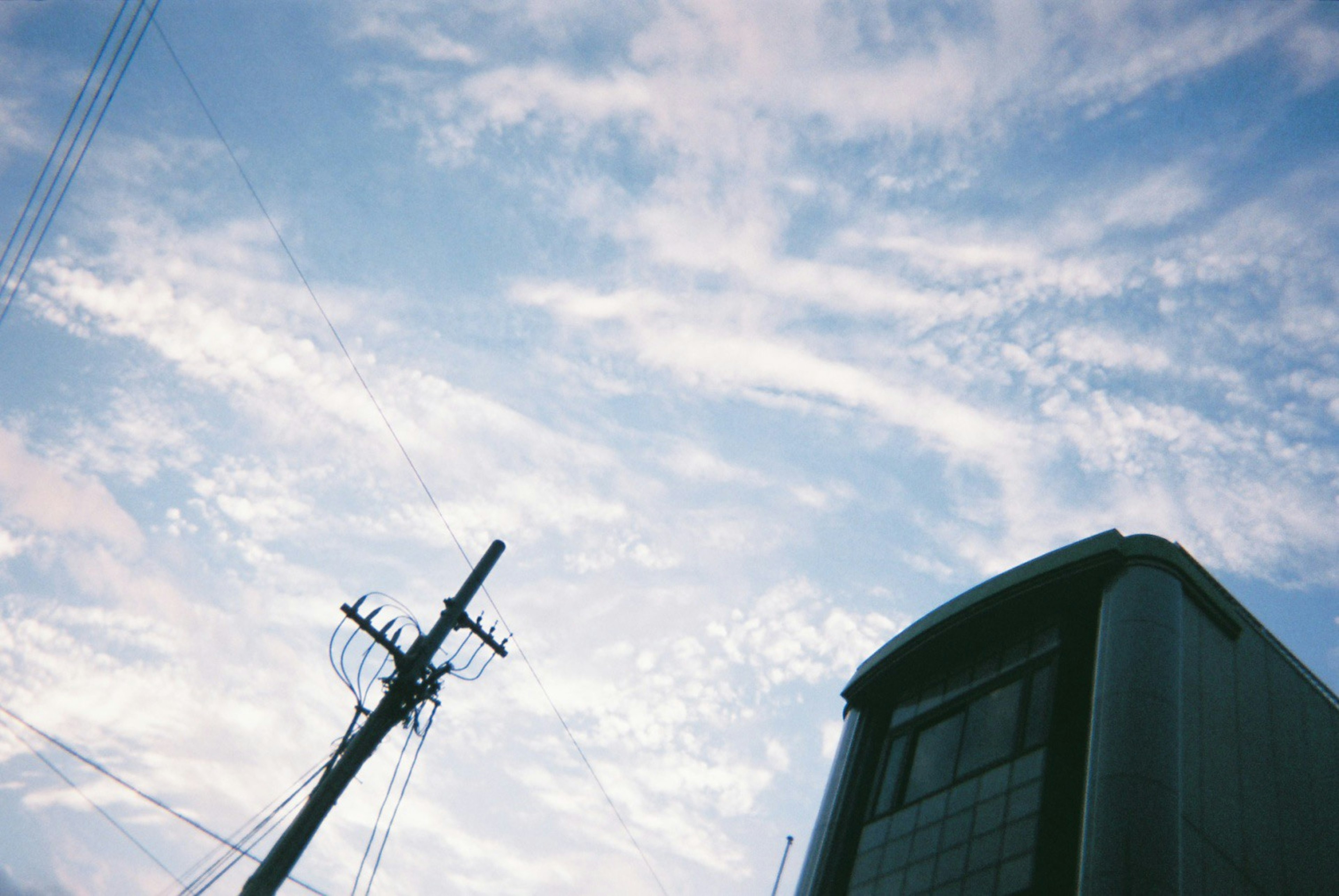 Himmel mit weißen Wolken und einem Strommast