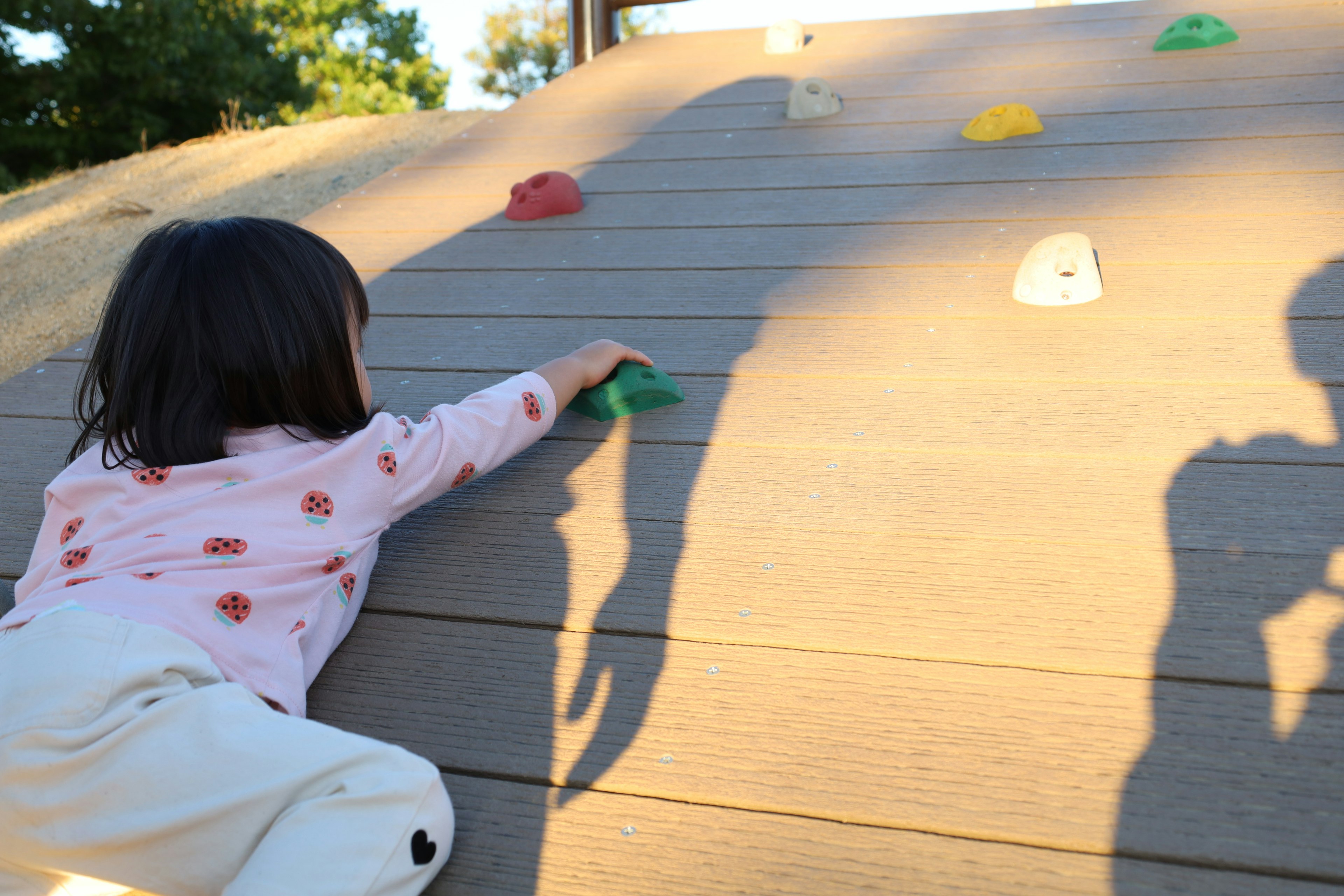 Kind, das an einer bunten Kletterwand auf einem Spielplatz klettert