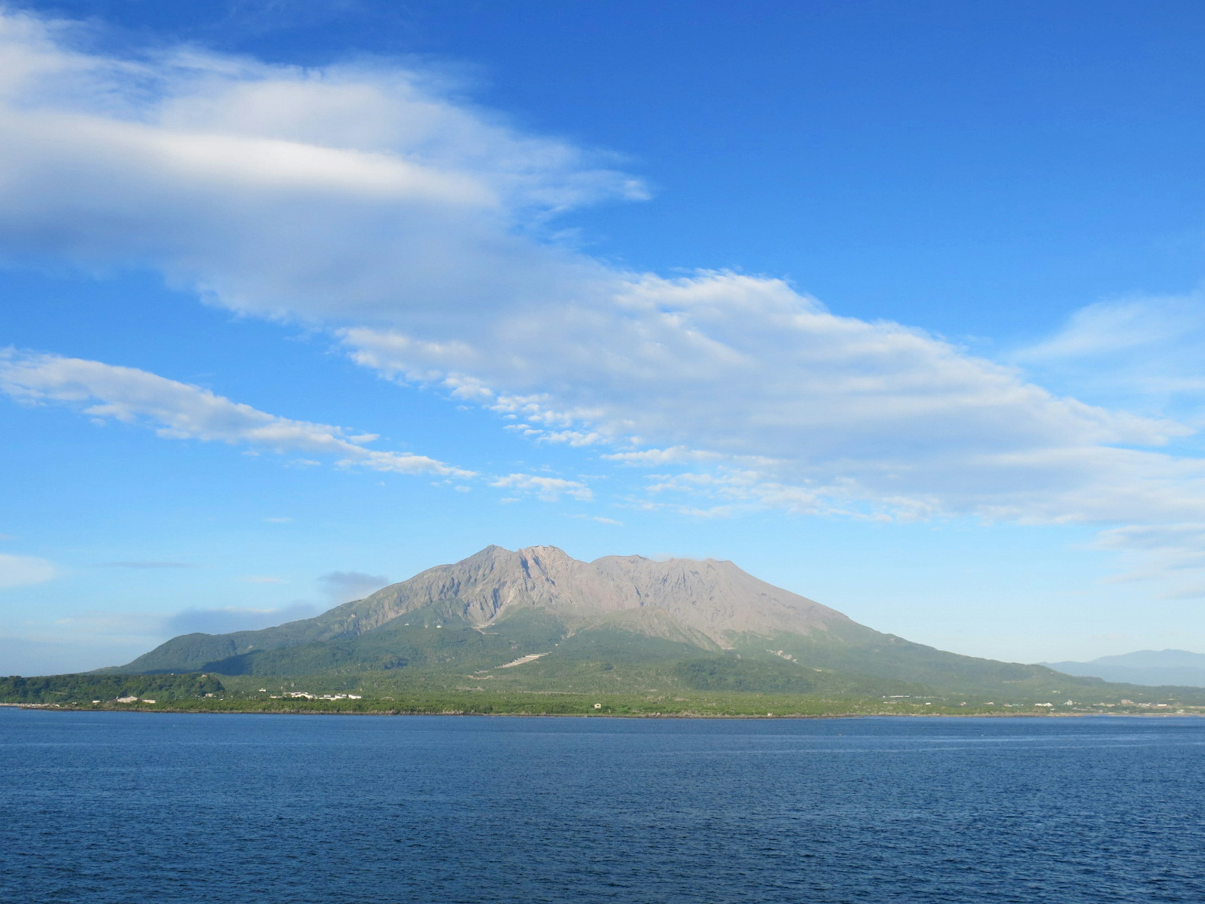 Pemandangan indah gunung hijau di bawah langit biru dengan awan tersebar