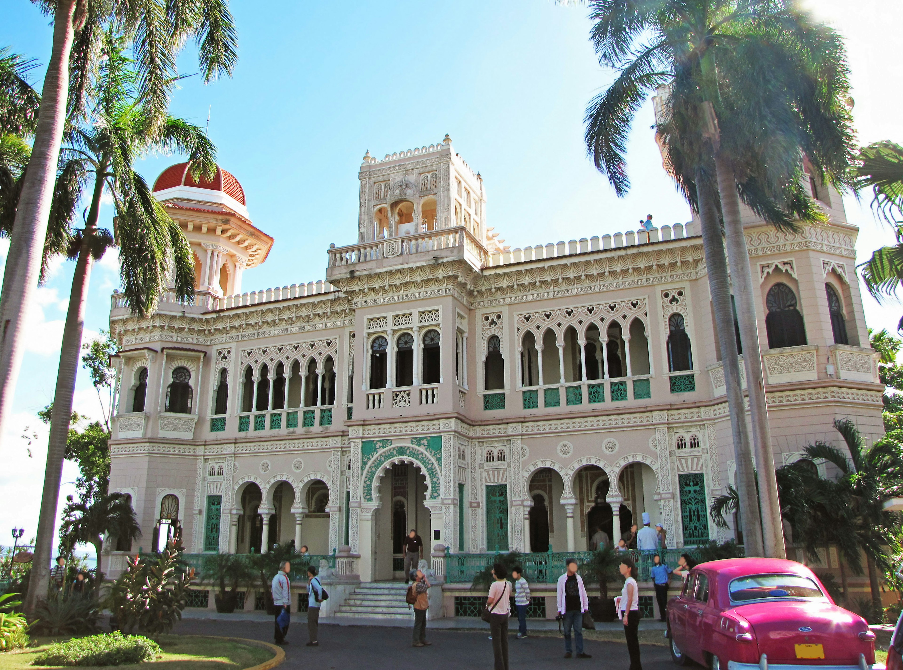 Beautiful colonial-style palace with palm trees and a pink taxi