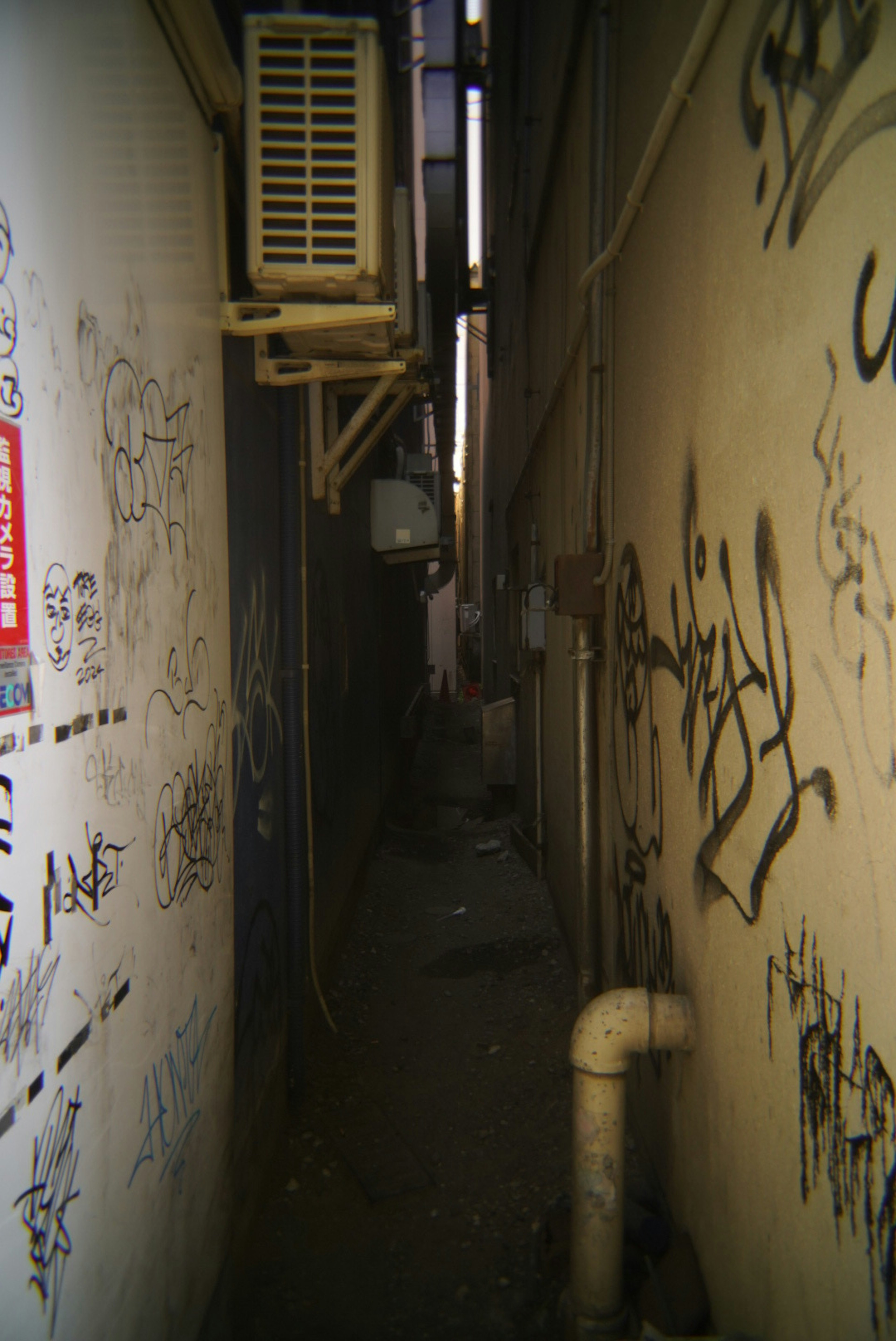 Narrow alley with graffiti-covered walls and an air conditioning unit