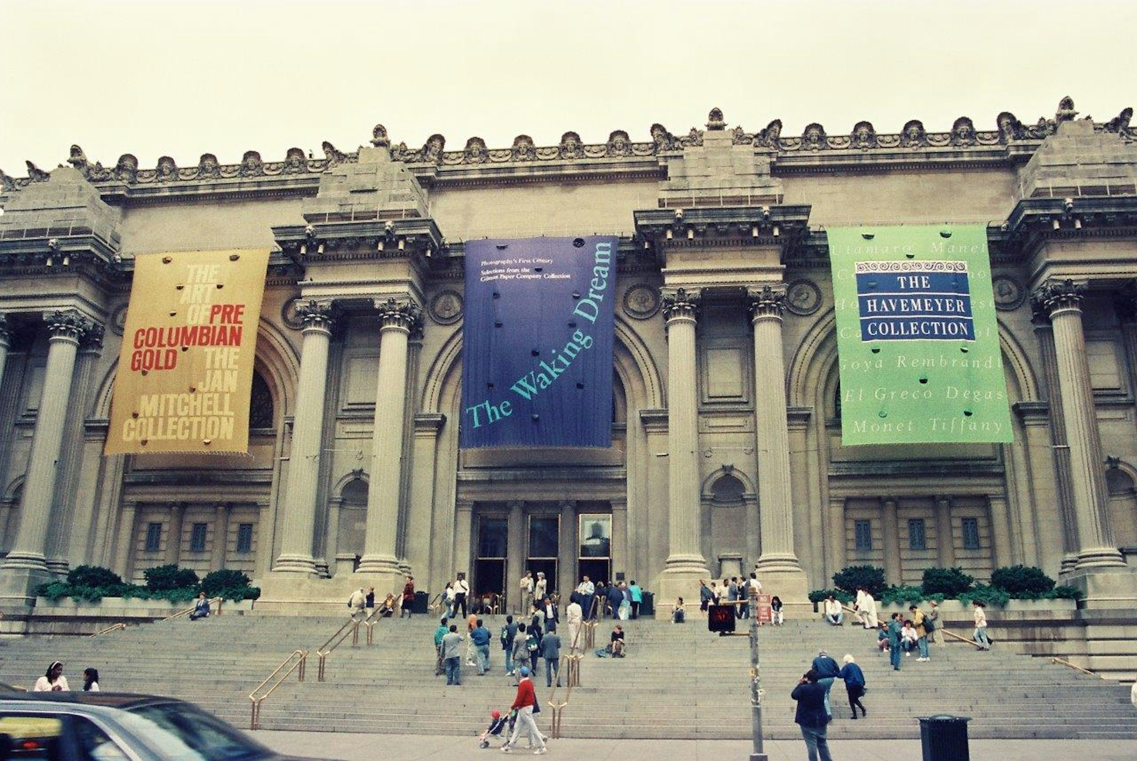 Fachada de un gran museo con pancartas coloridas y visitantes