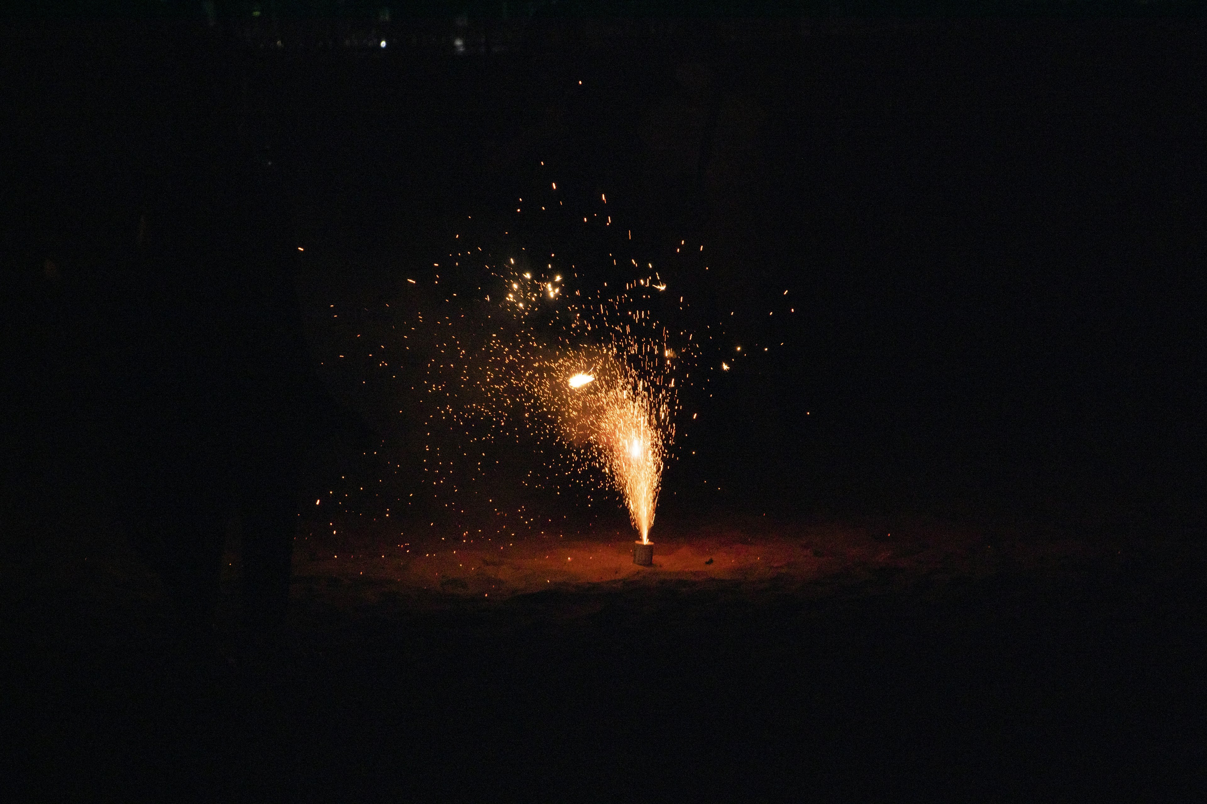 Firework fountain emitting sparks against a dark background