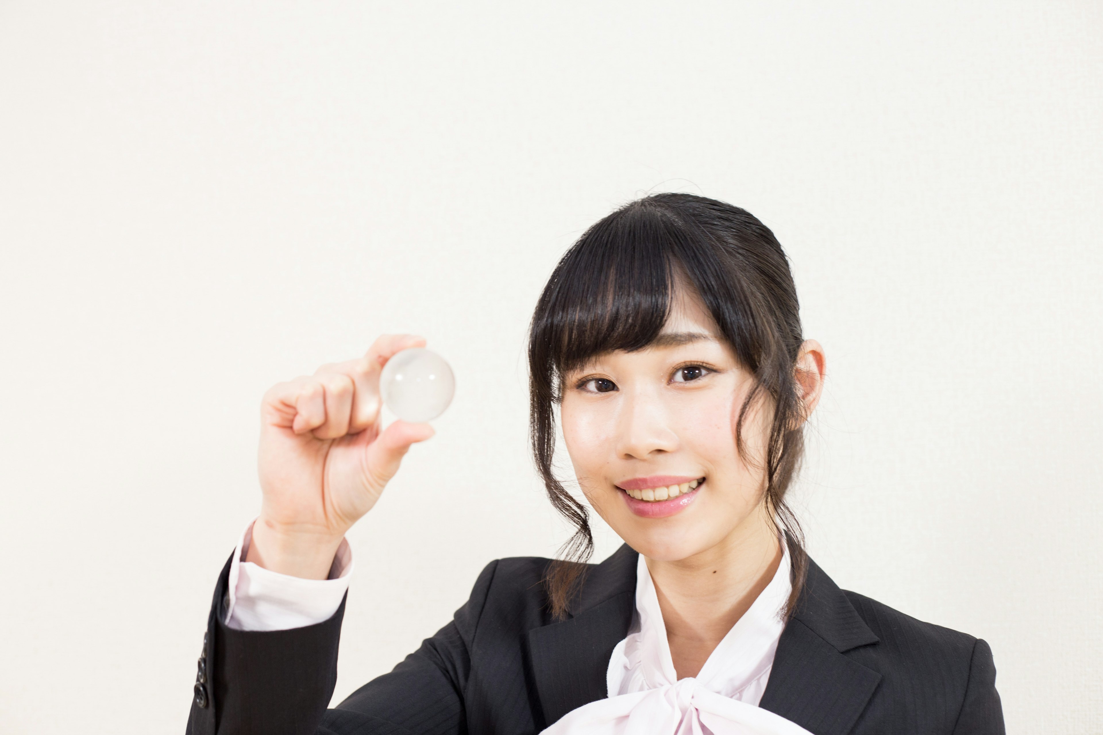 A woman in business attire smiling while holding a coin