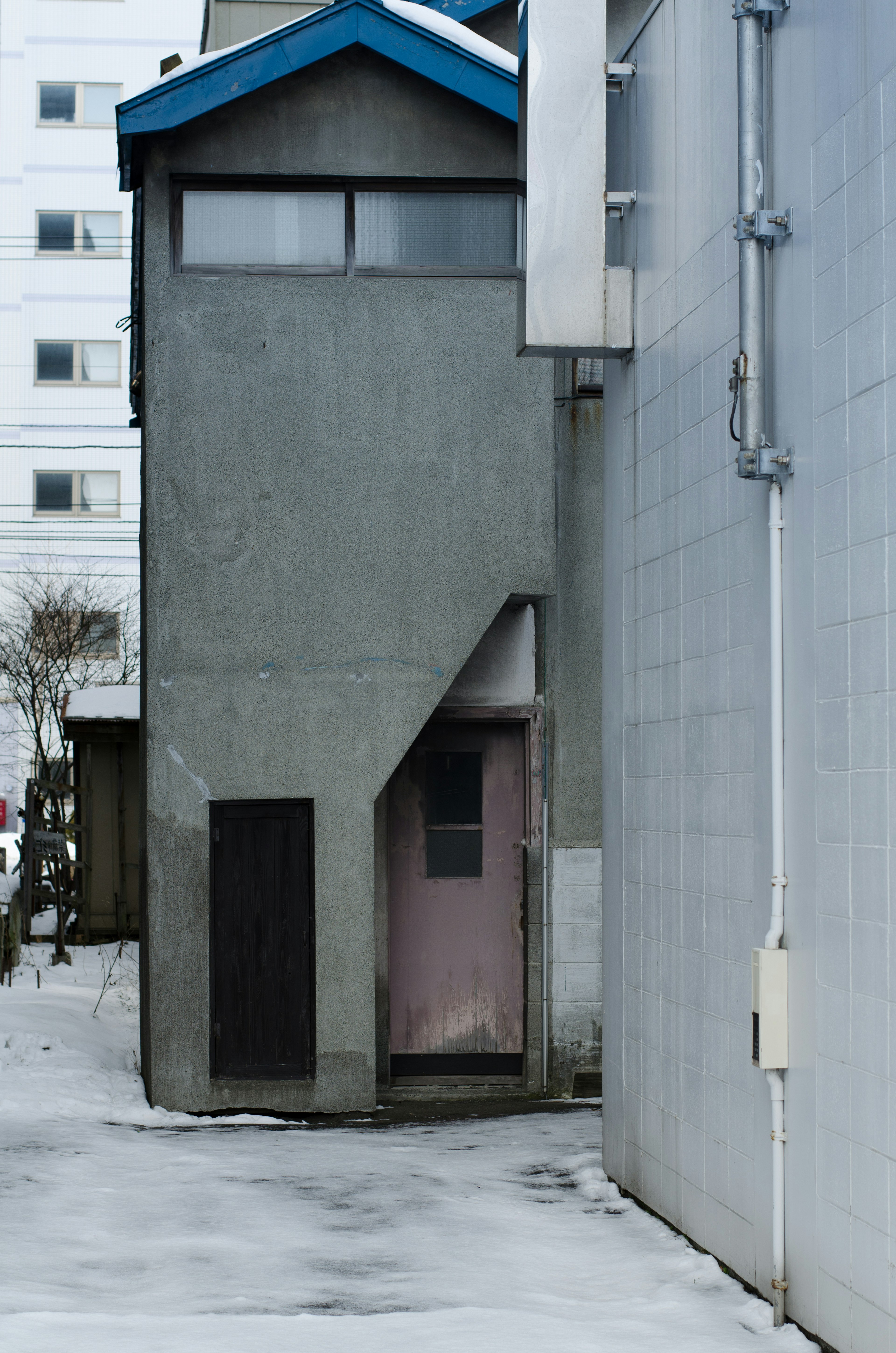 Allée étroite avec un bâtiment en béton et une porte rose