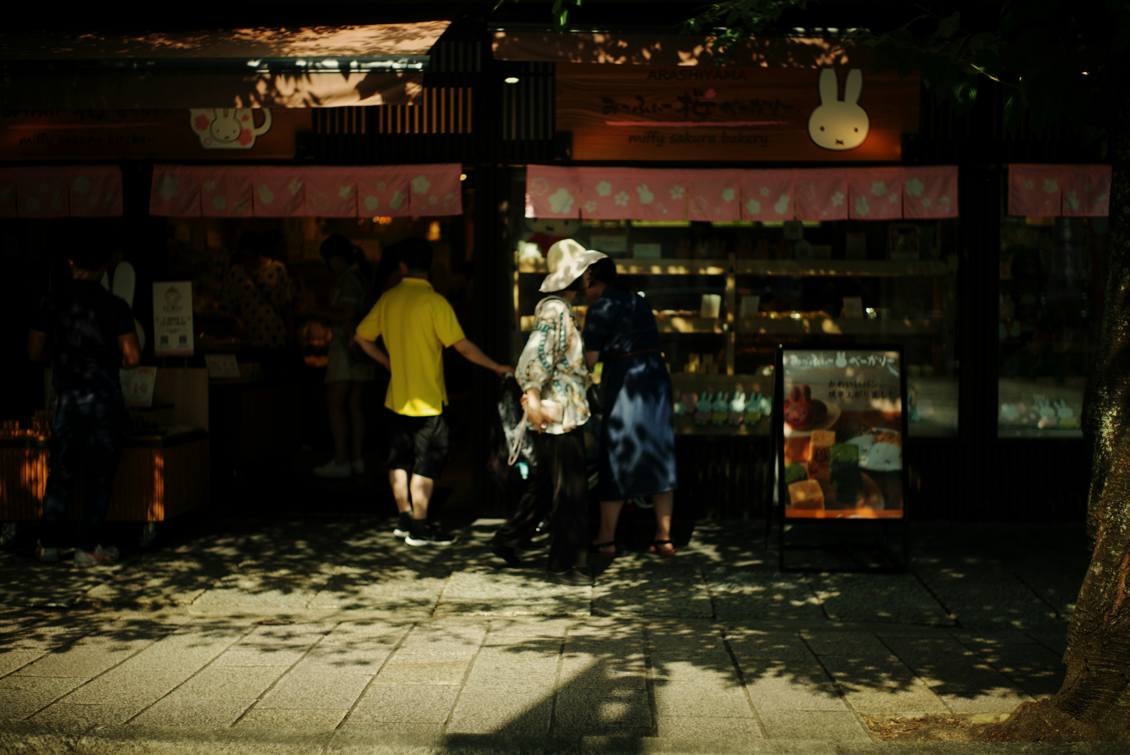 Personas charlando frente a una tienda escaparate colorida con sombras en la calle