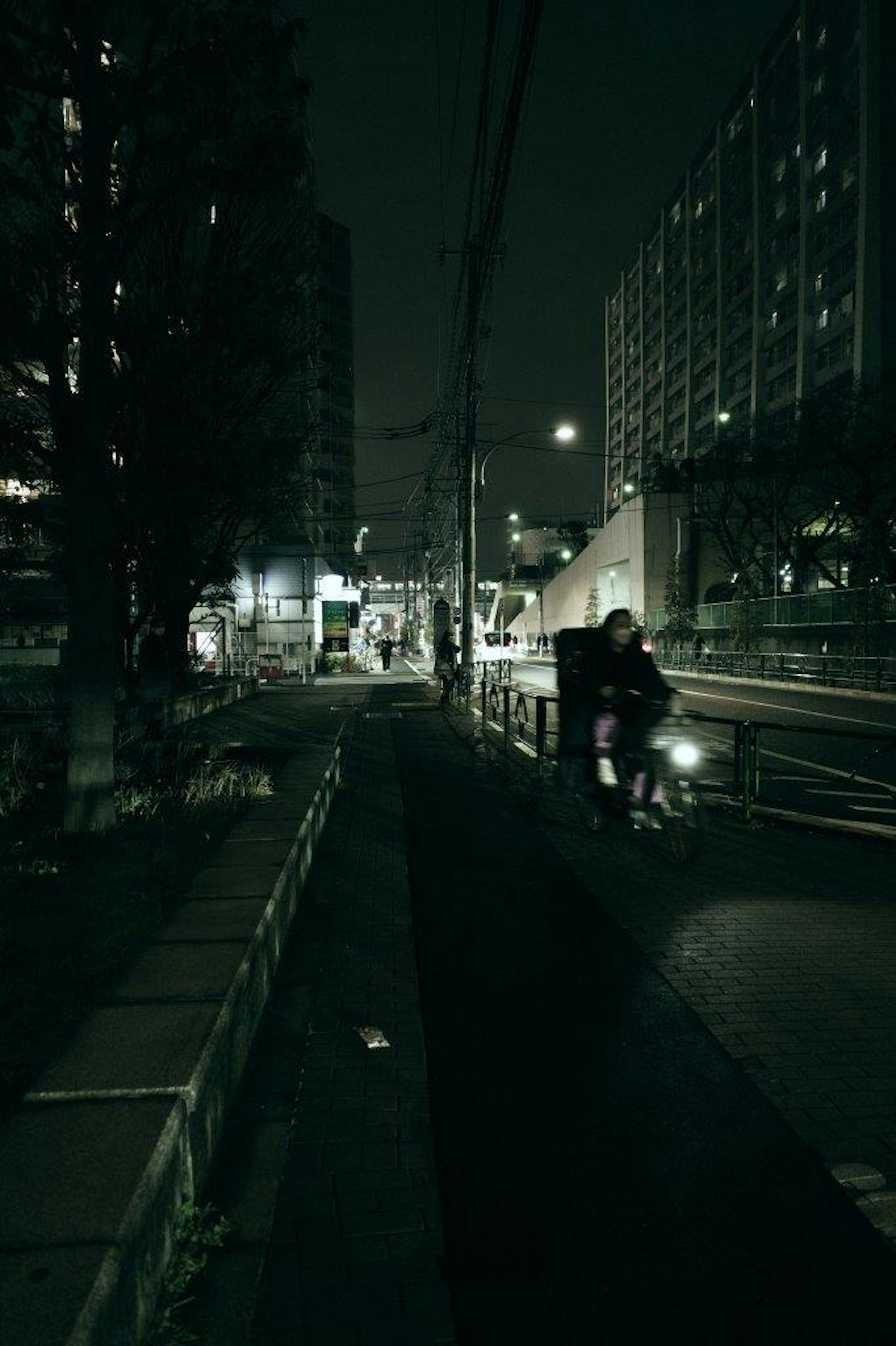 暗い夜の街角で歩行者とバイクが通る風景