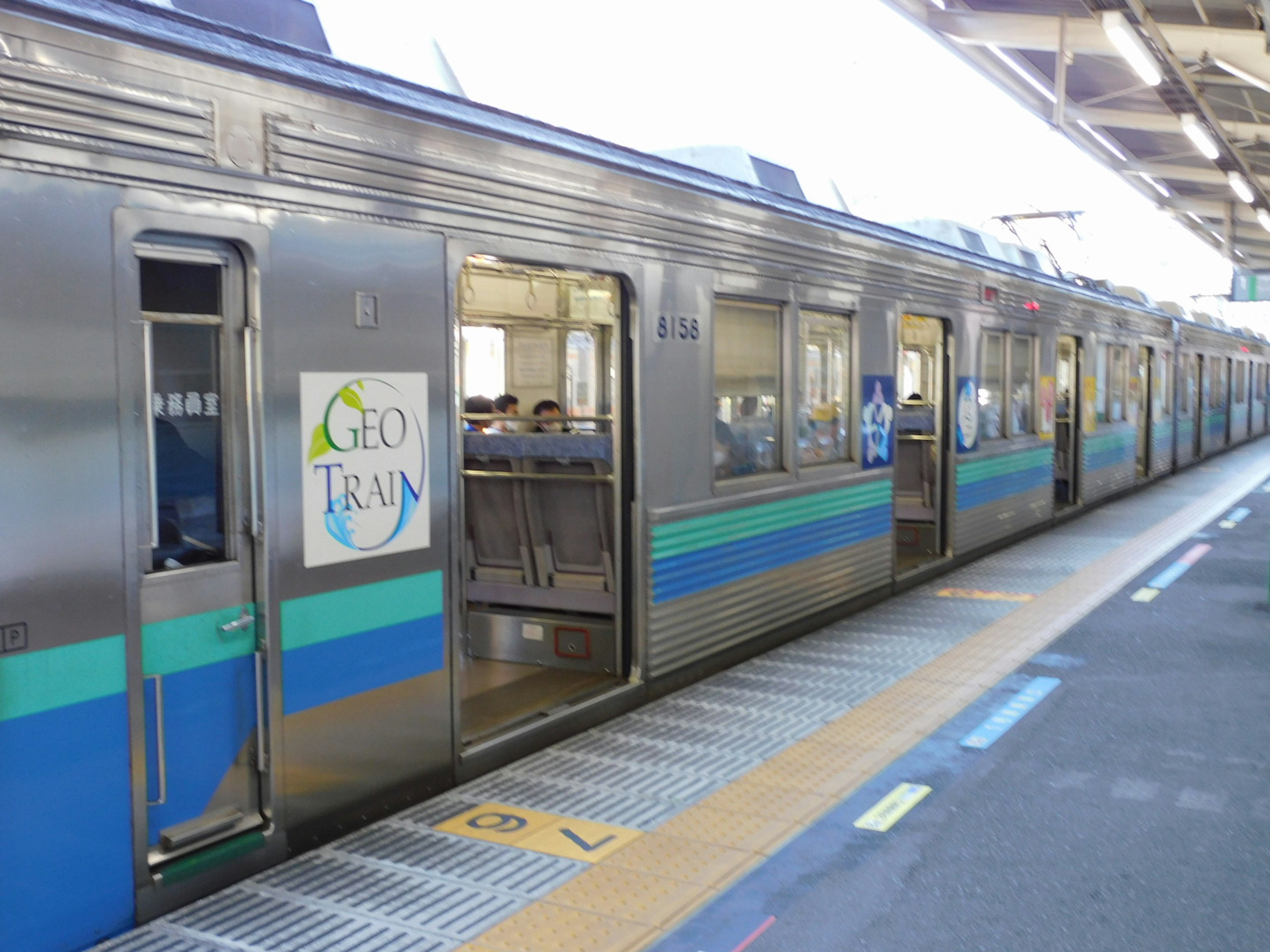 青と銀の電車が駅に停車中で乗客が見える