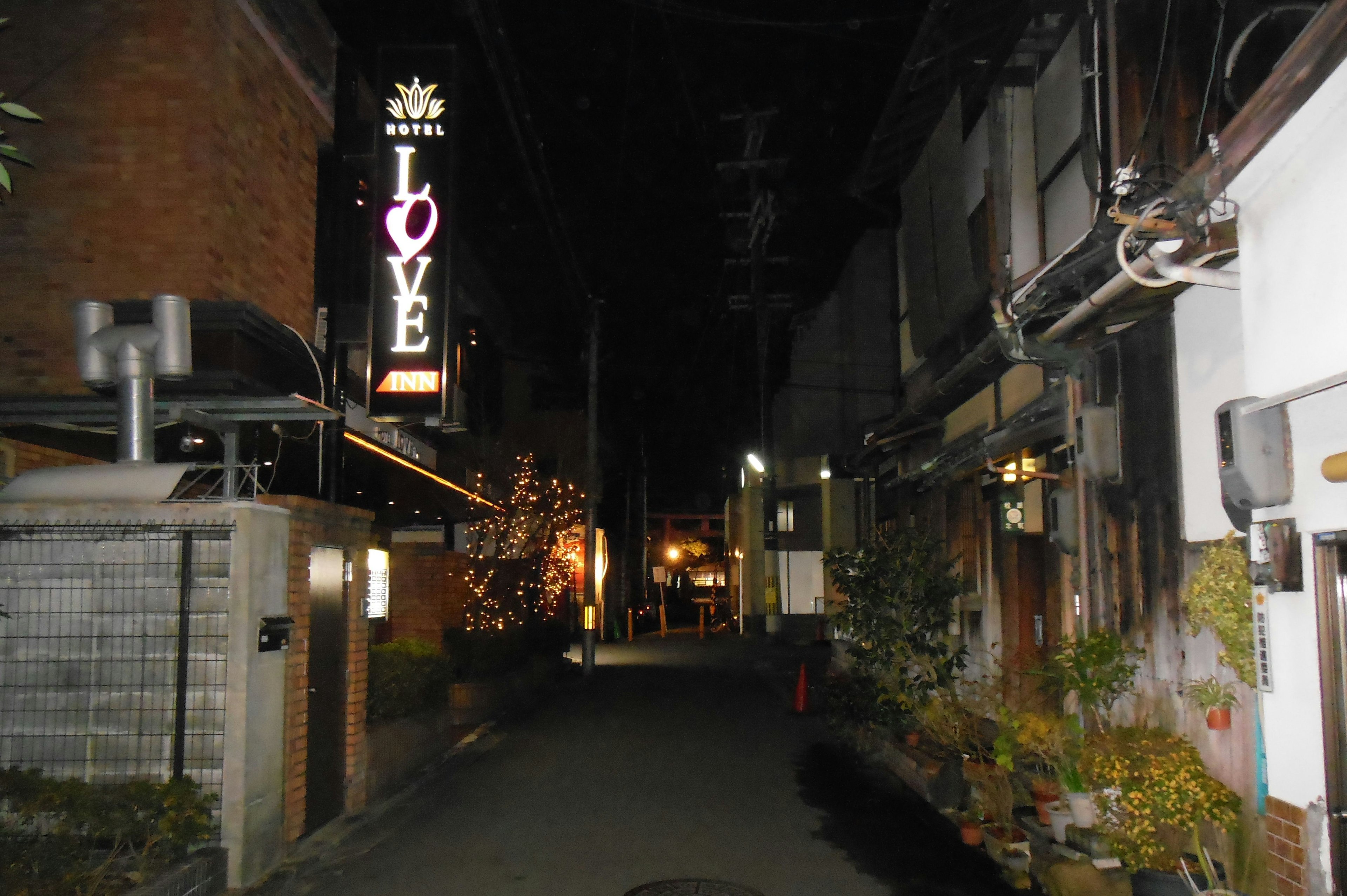 暗い路地にある「LOVE」のネオン看板と古い建物