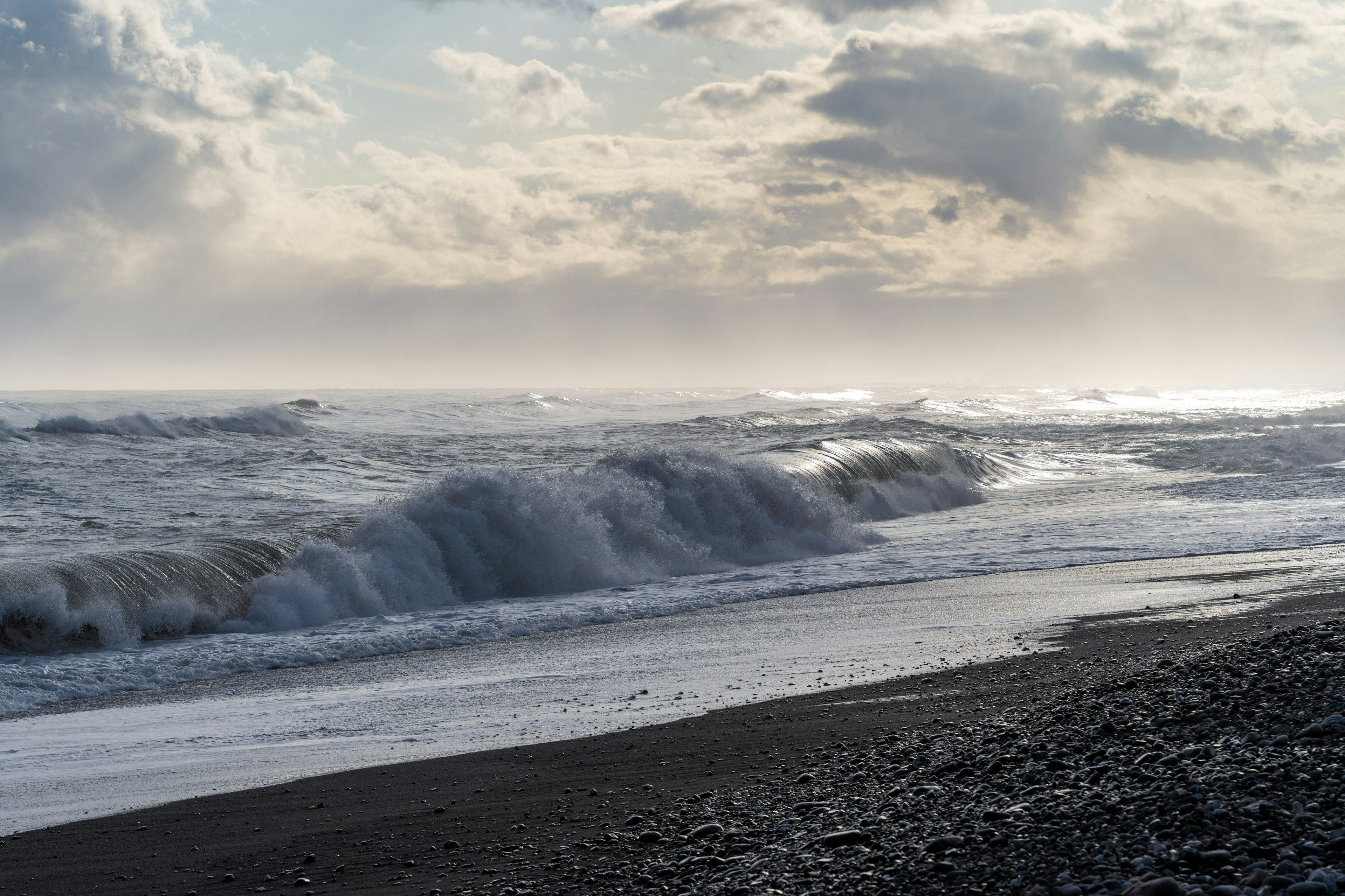 Un mar tempestuoso con olas rompiendo en una playa de guijarros