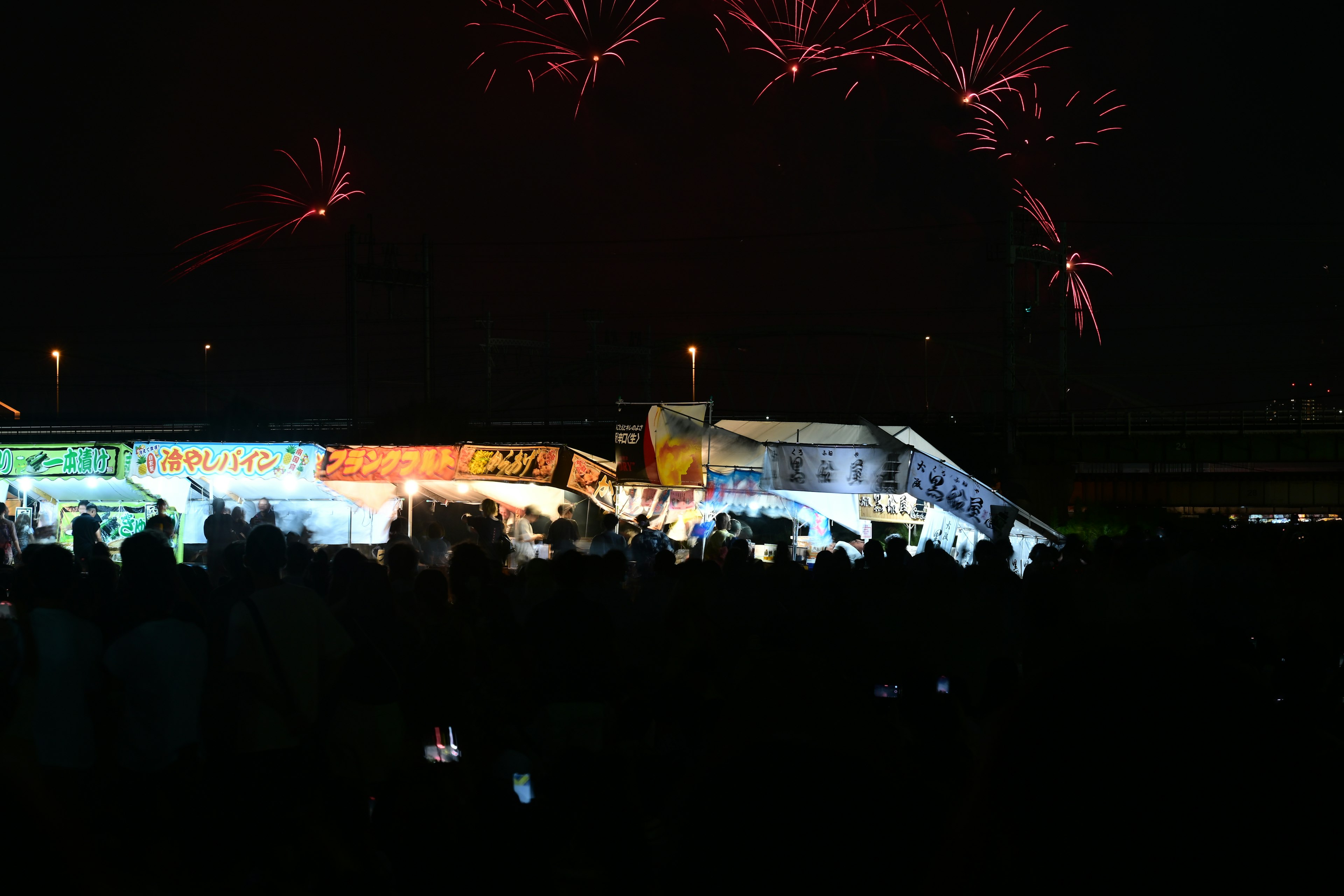 A vibrant festival scene with fireworks illuminating the night sky and a crowd gathered