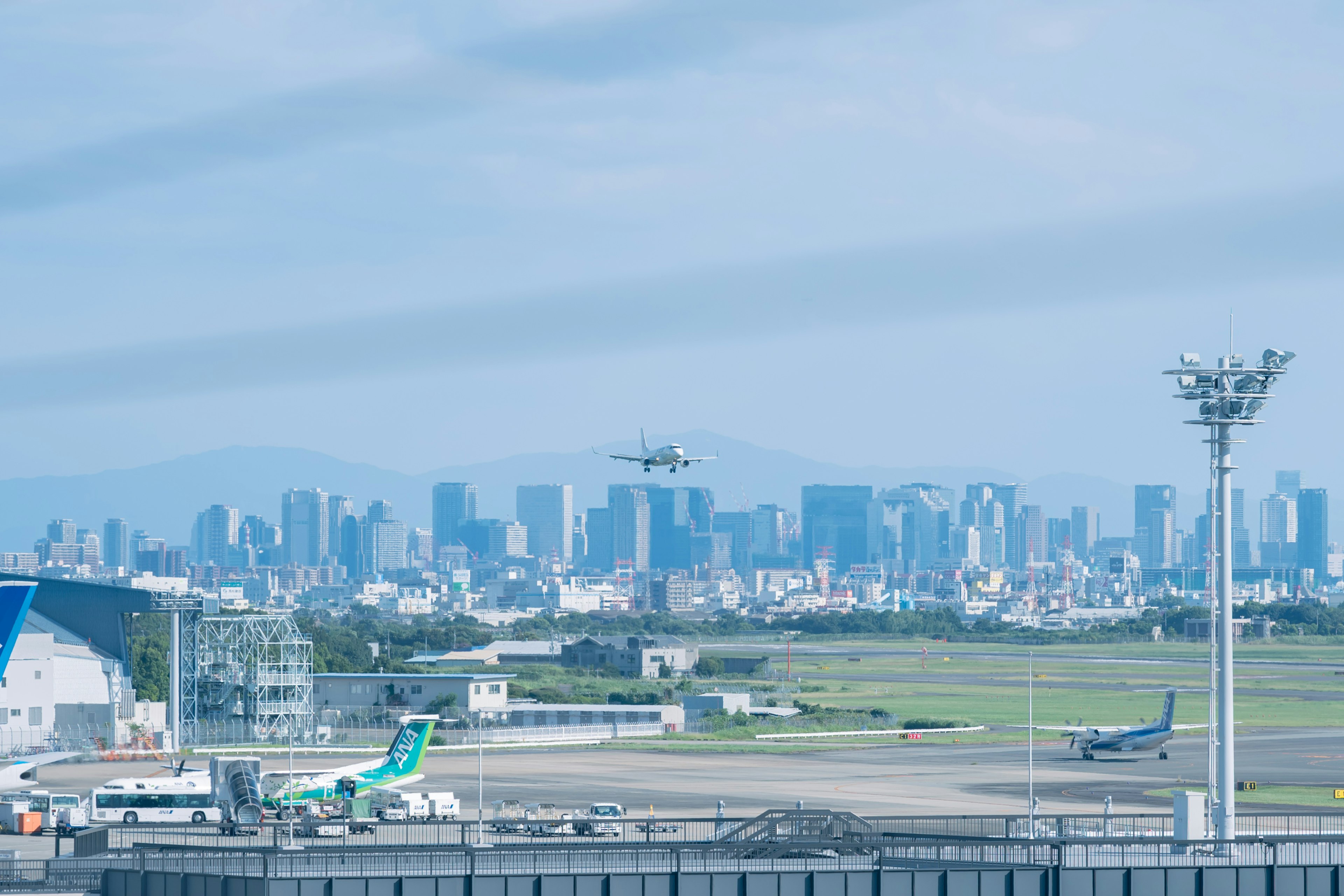 Aereo in decollo con pista aeroportuale e skyline cittadino sullo sfondo