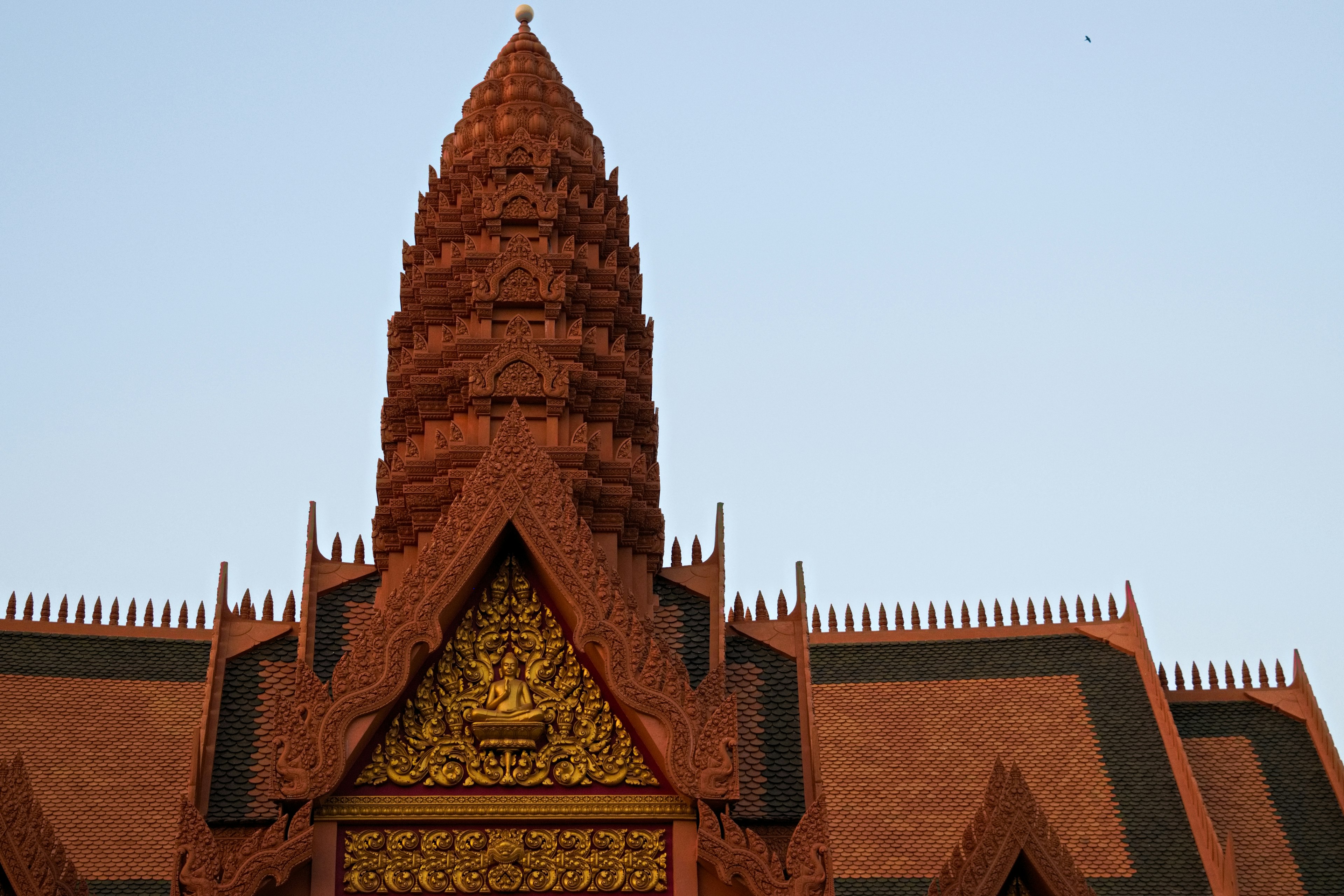 Upper part of a red temple featuring a spire and golden decorations