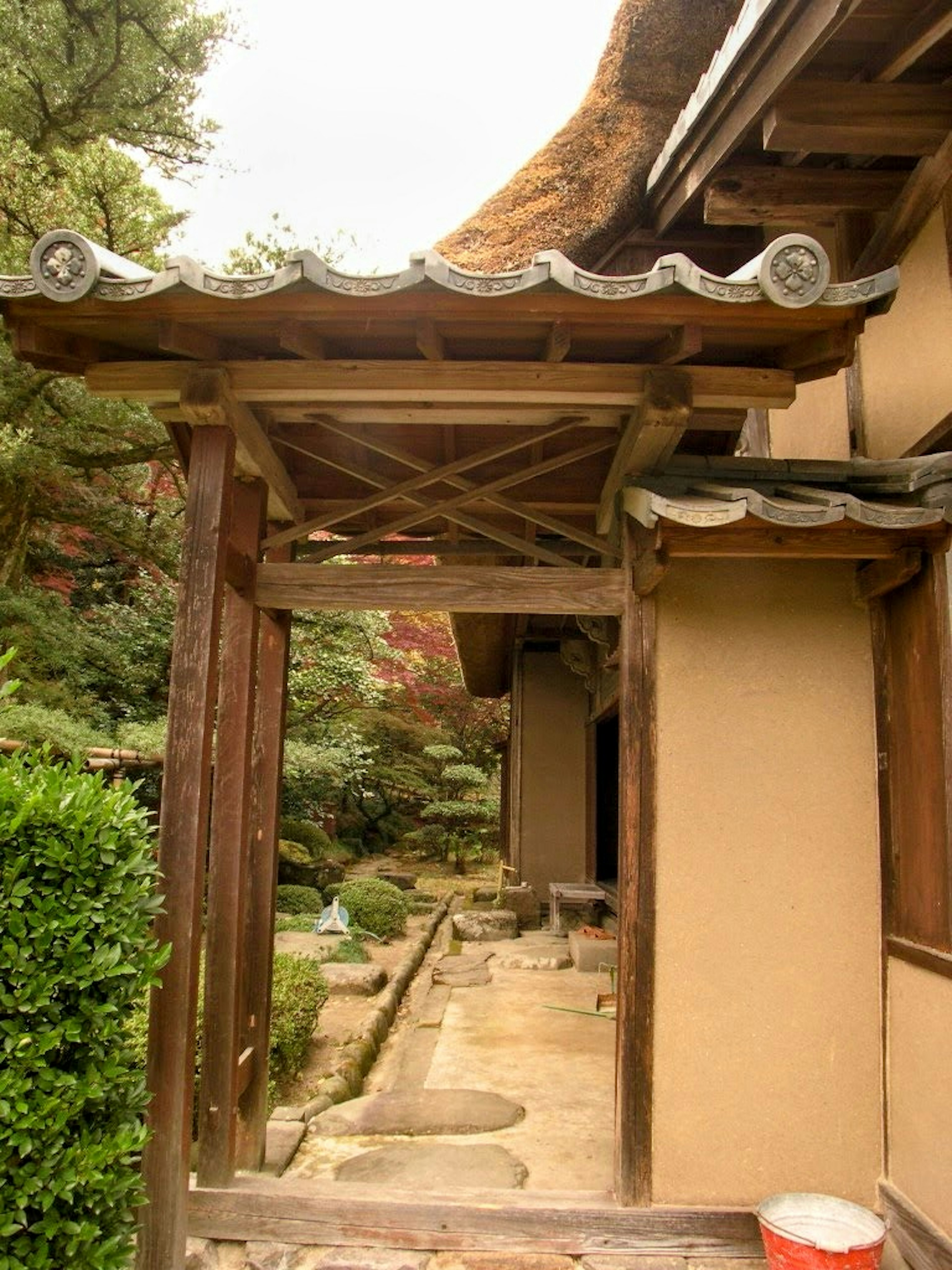 Entrée d'une maison japonaise traditionnelle avec une porte en bois et un jardin de toit de chaume