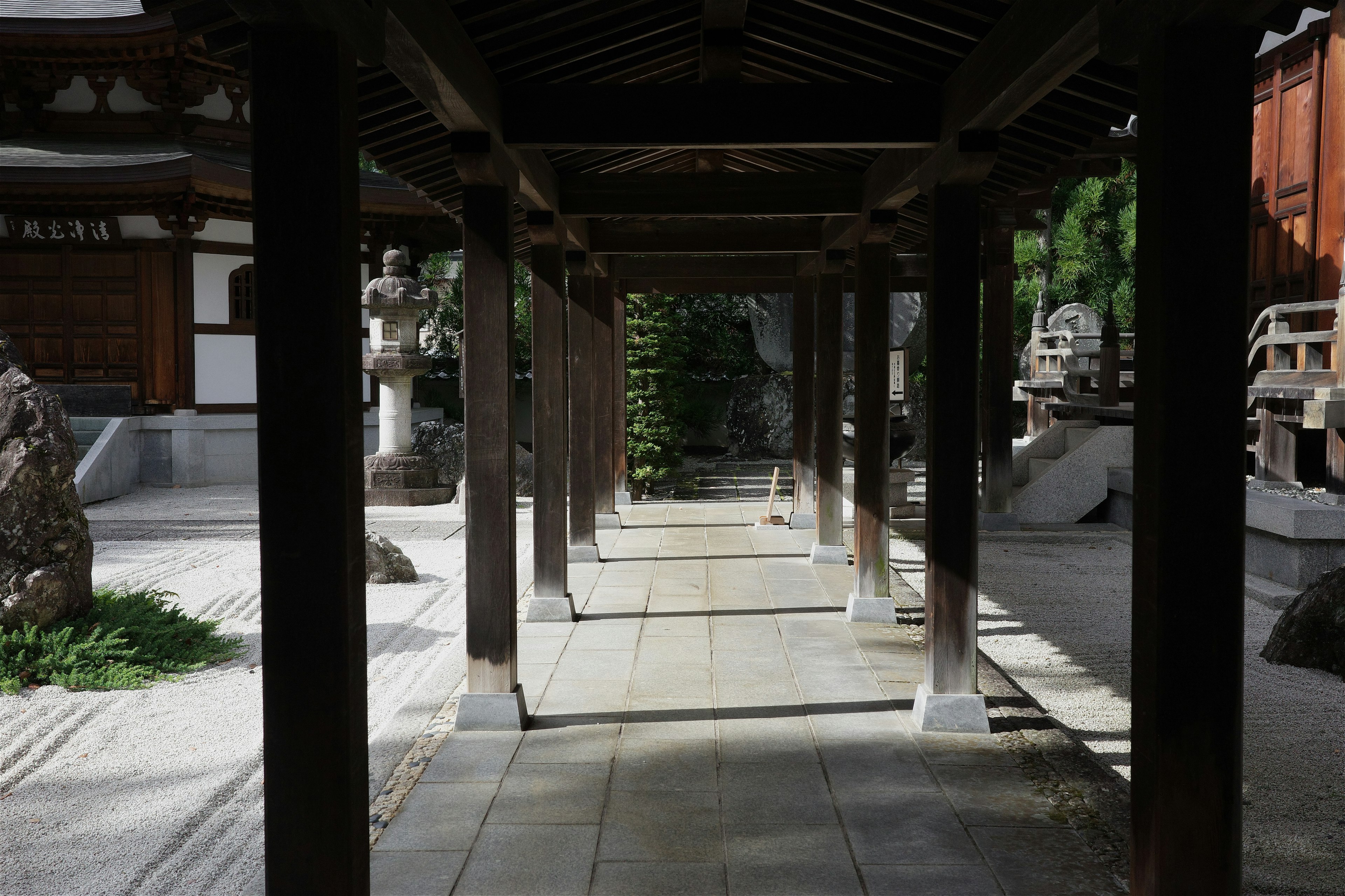 Koridor tradisional Jepang dengan tiang kayu dan taman batu