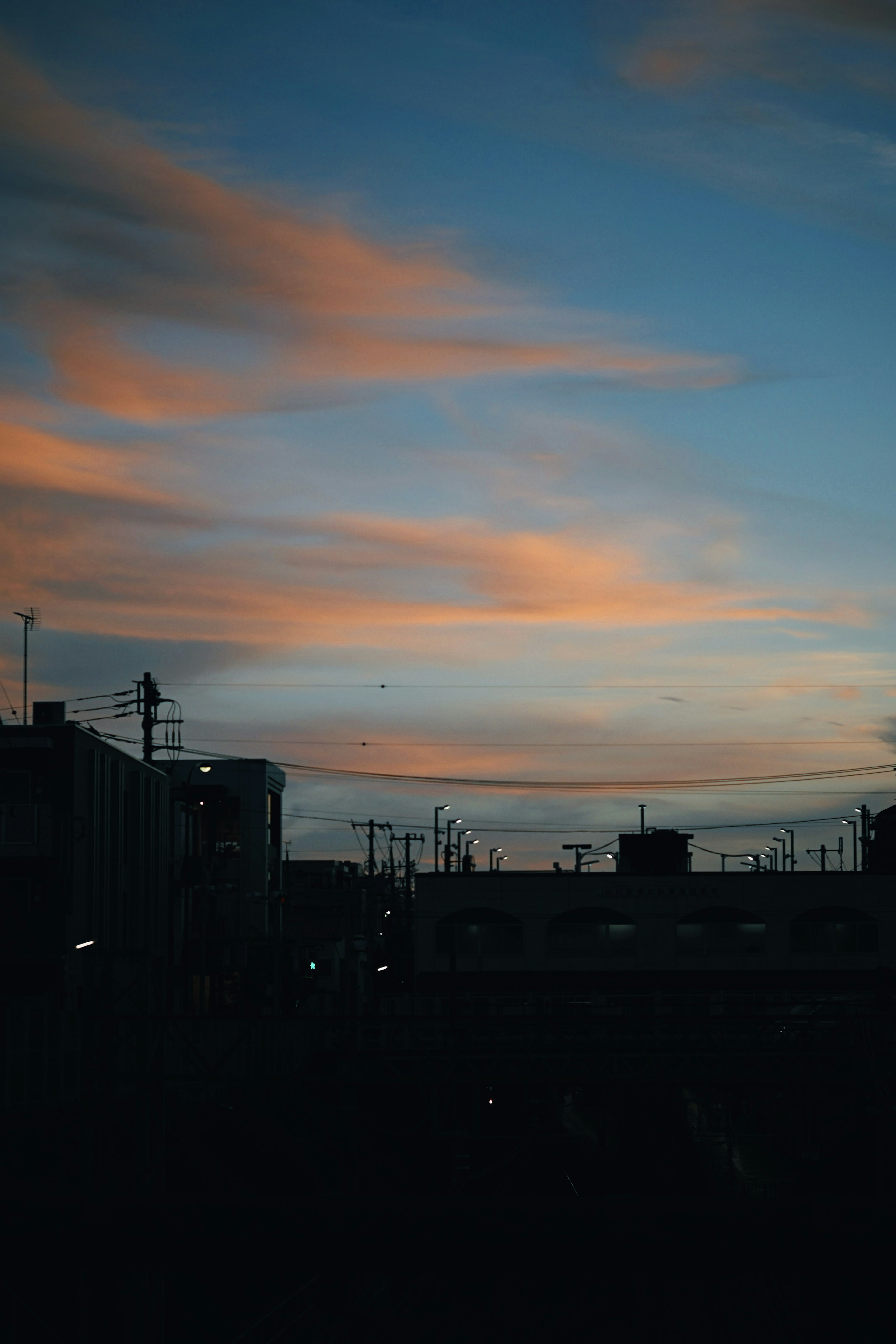 Silhouette of buildings against a sunset sky with soft clouds