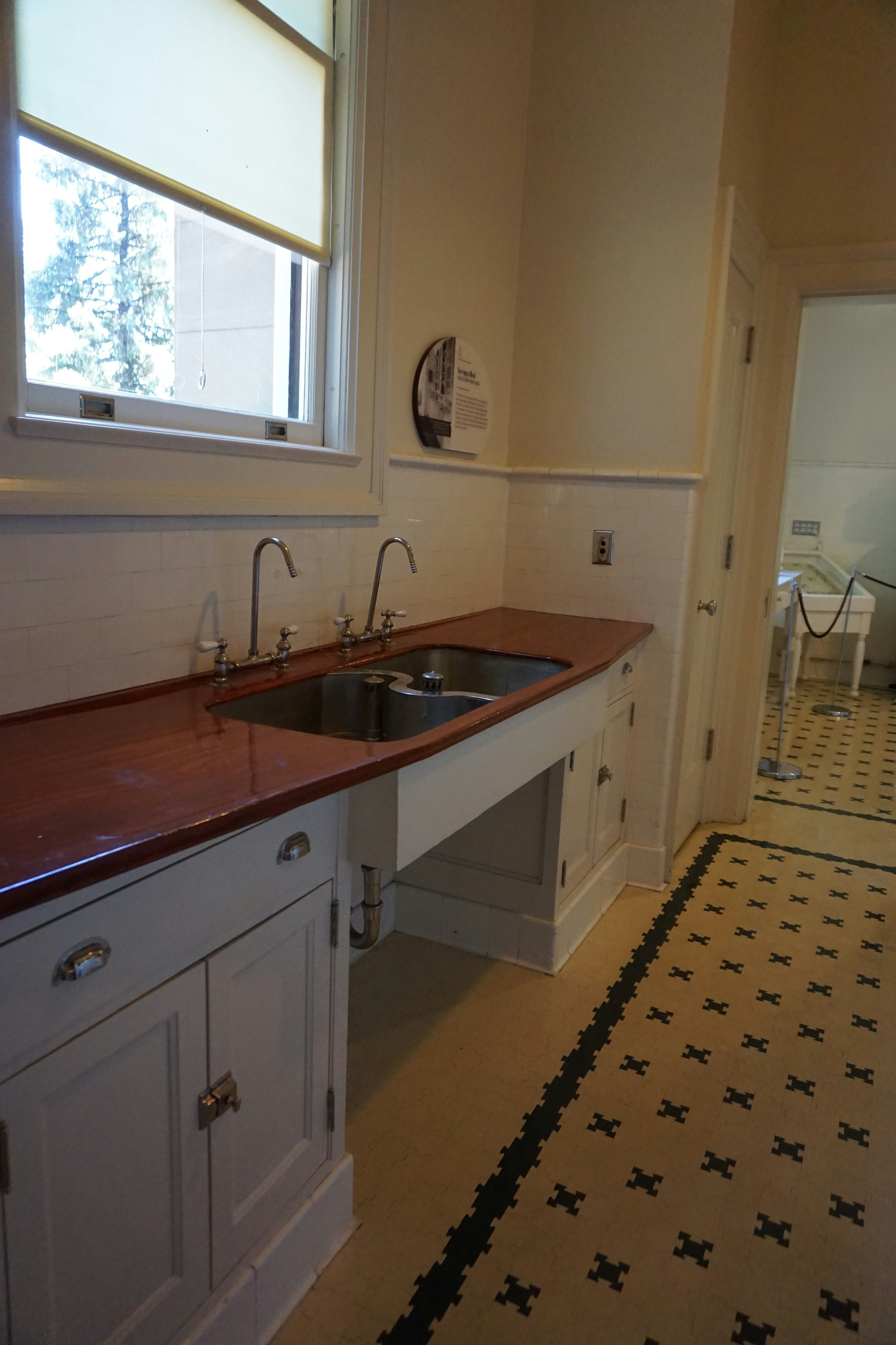 Bright kitchen corner featuring red countertop and sink with white cabinets and black tiled floor