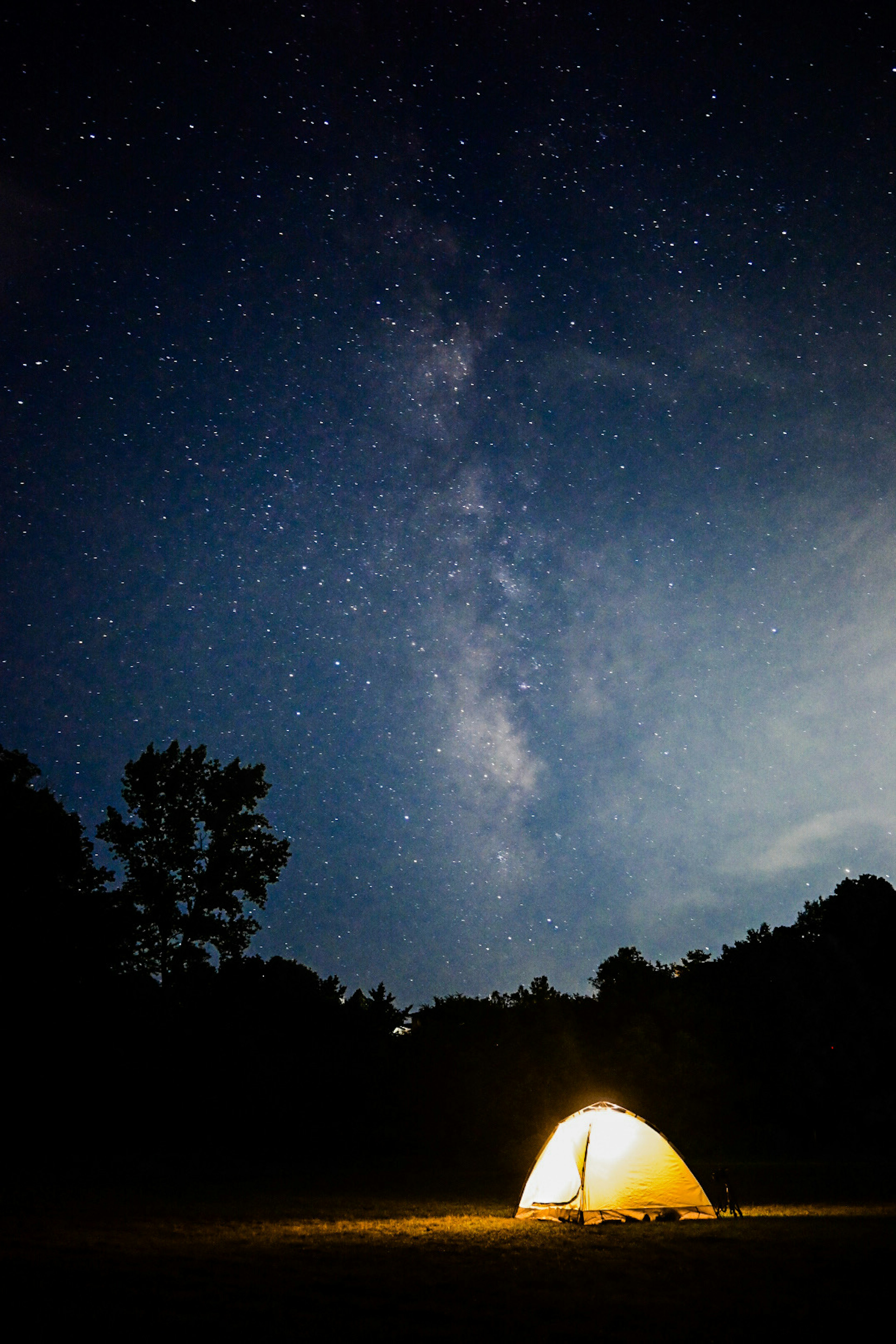 Tent illuminated under a starry night sky featuring the Milky Way