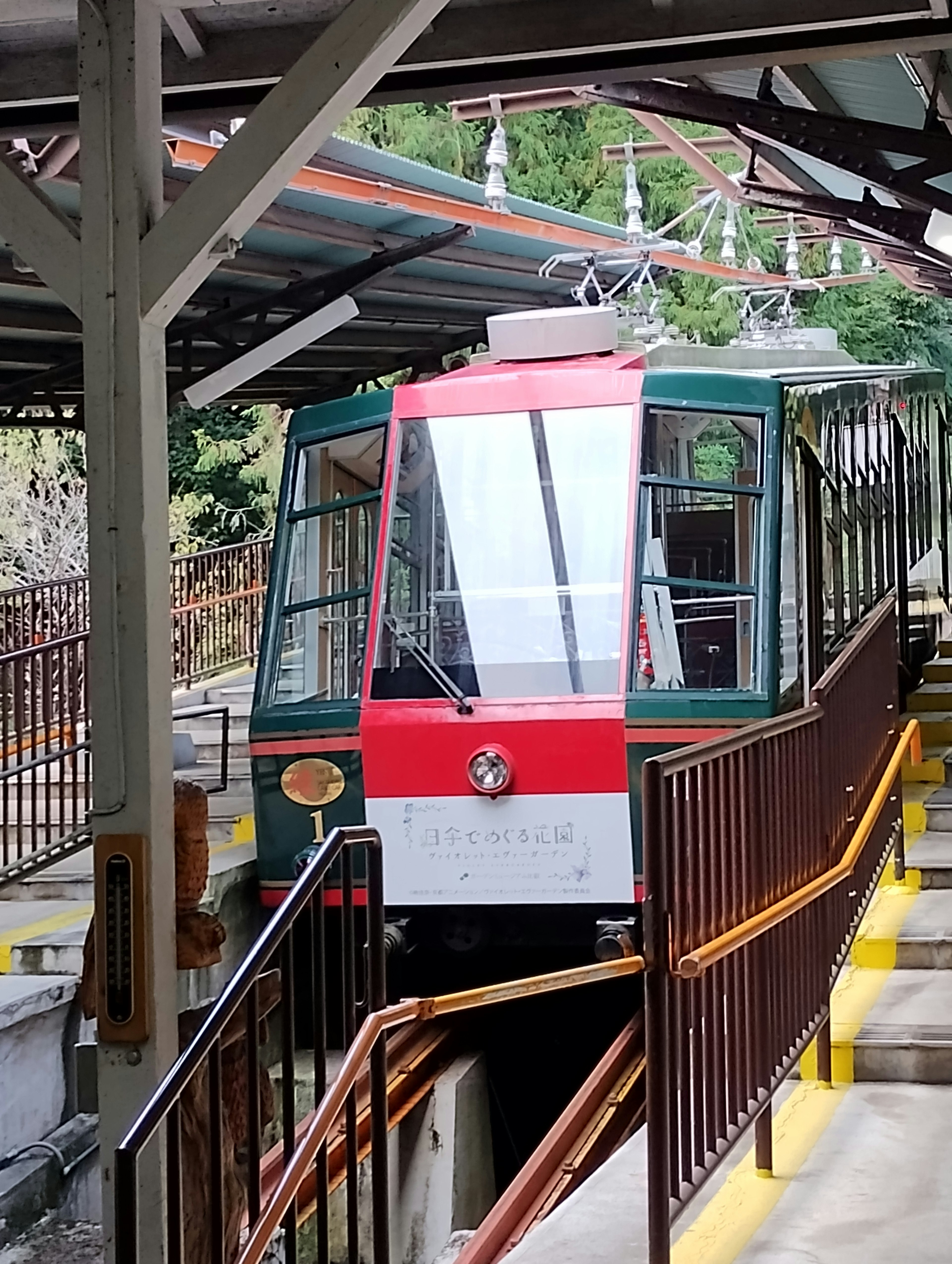 赤と緑のケーブルカーが駅に停車中