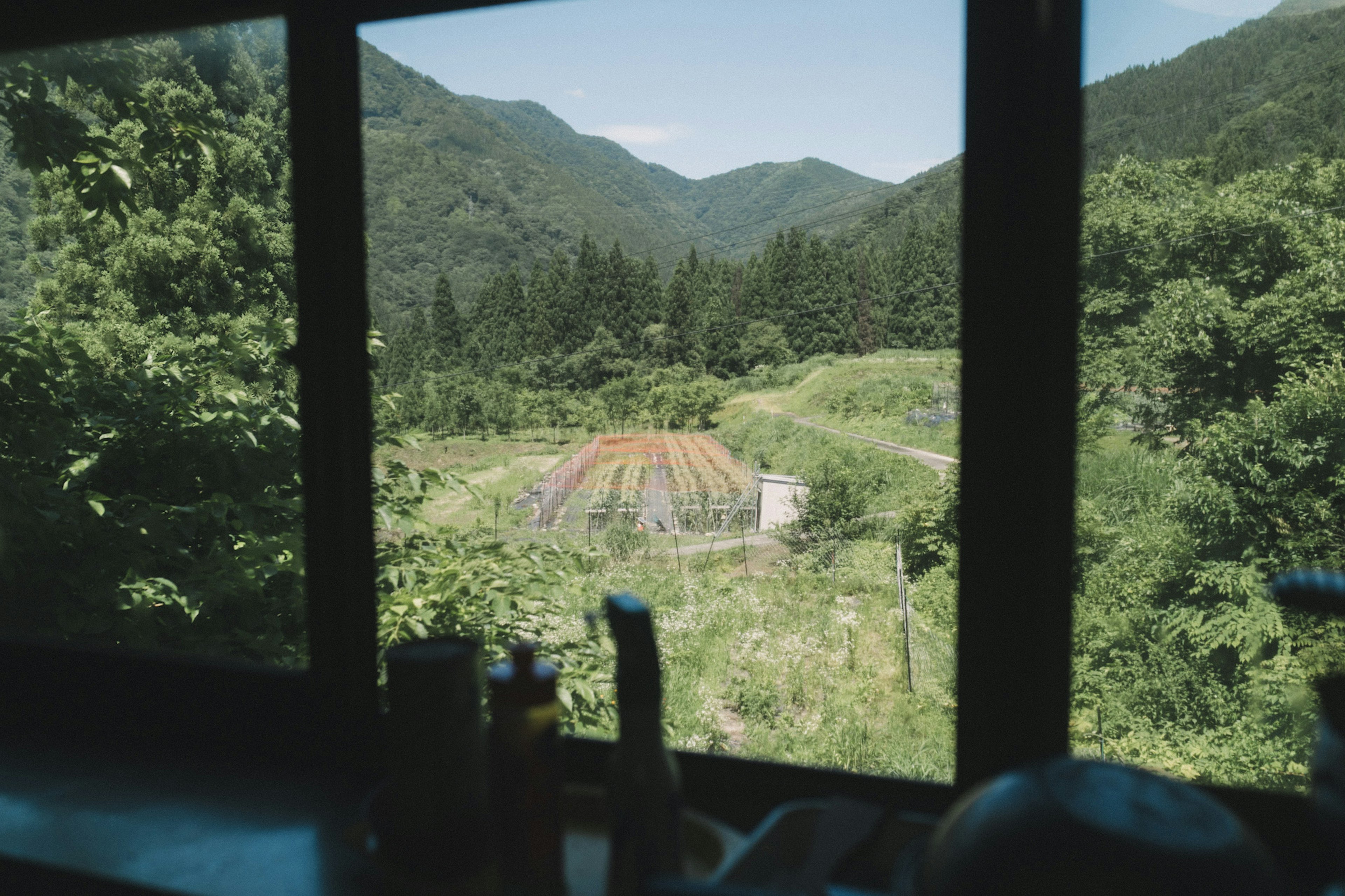 Blick aus einem Fenster umgeben von Bergen und Grün