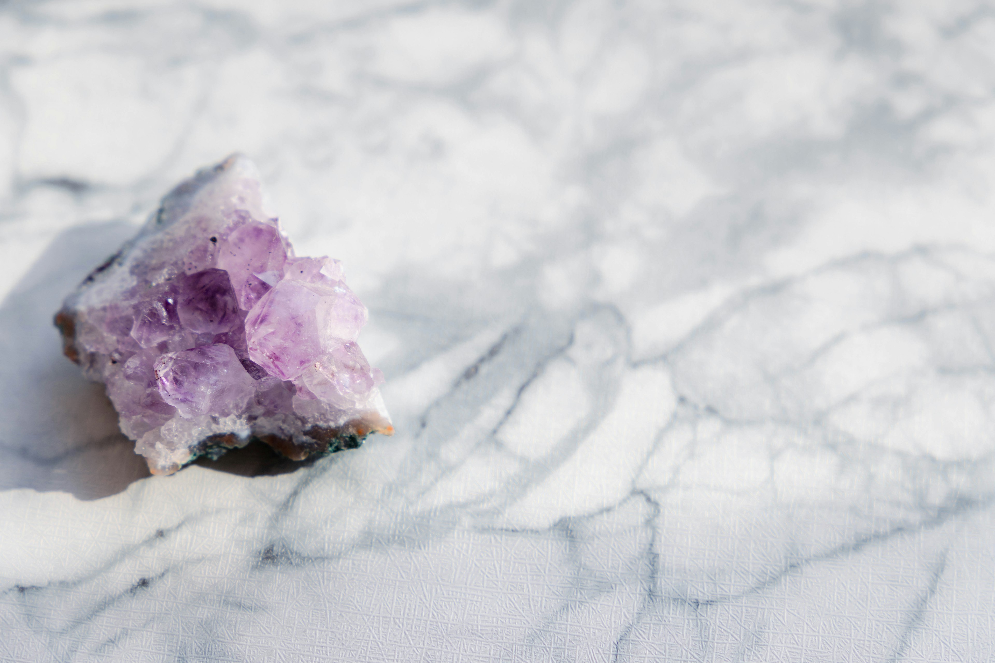 Amethyst crystal on a marble surface with light reflections