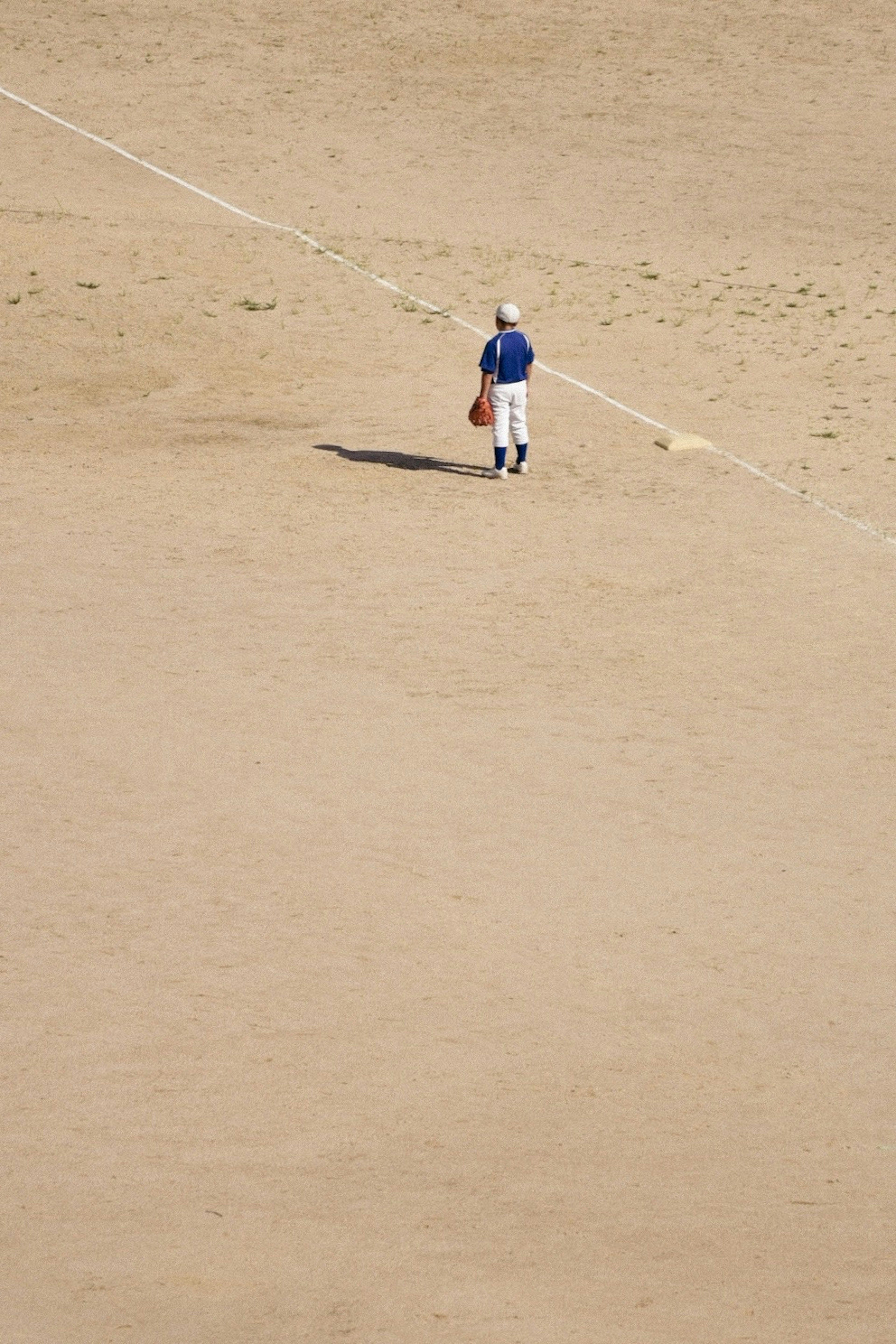 Baseball player standing alone on a sandy field