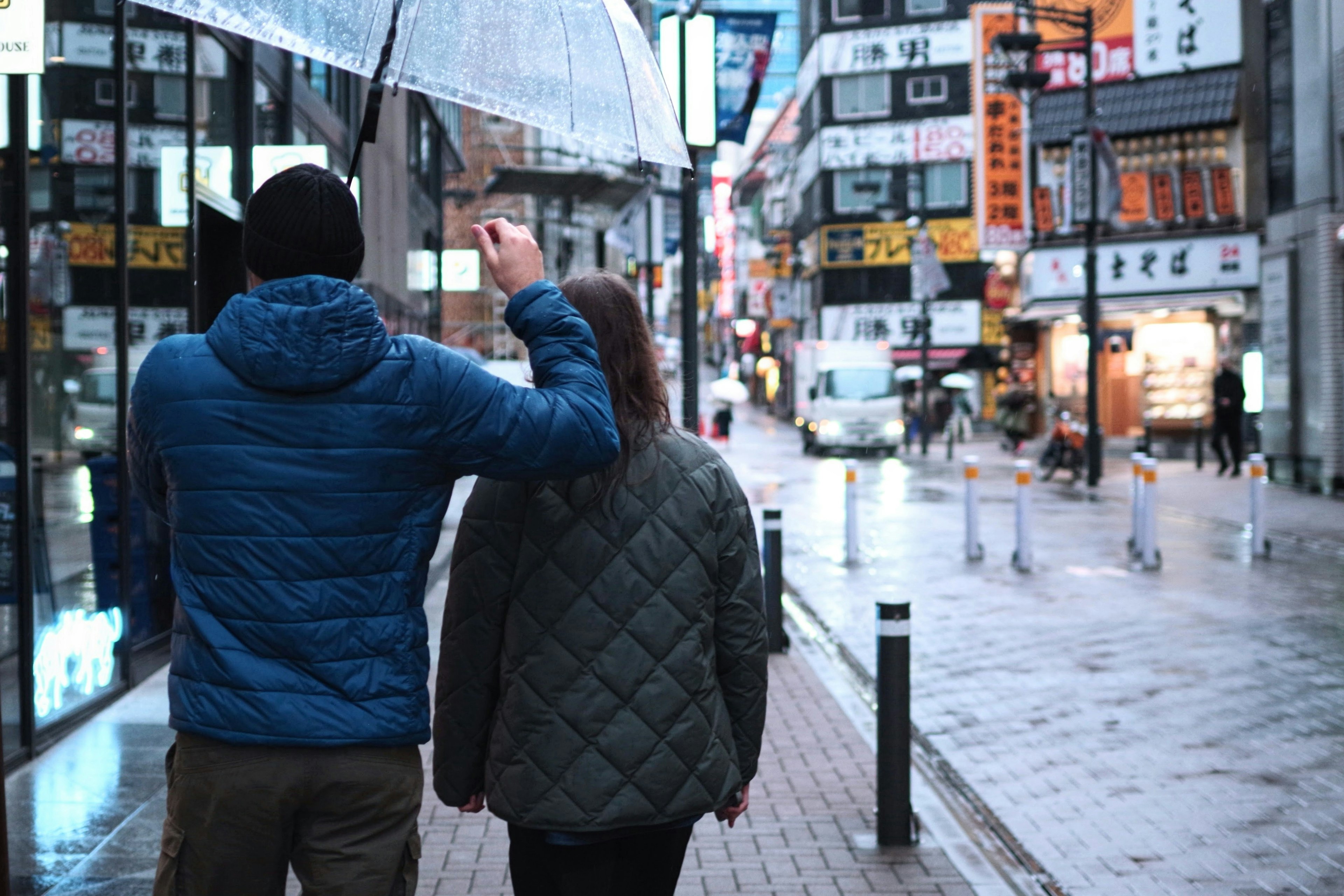 一对情侣在雨中撑着伞走在城市街道上