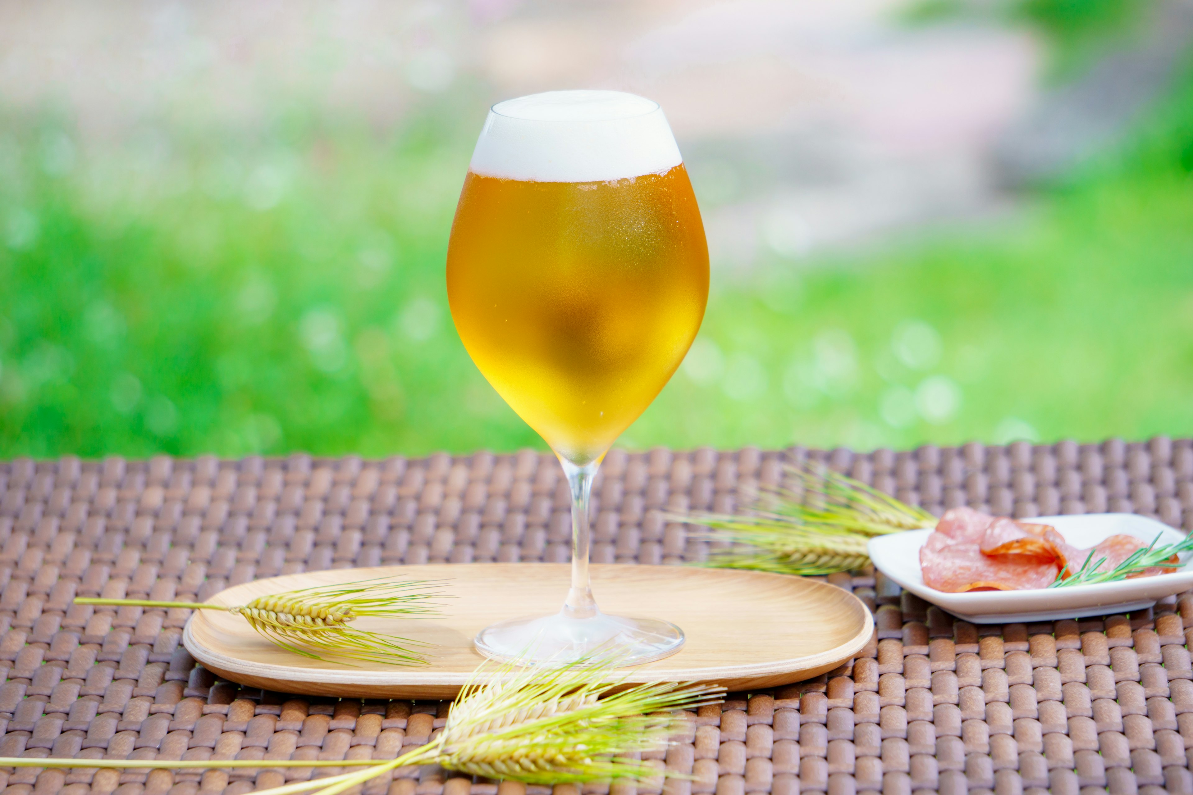 A glass of beer with a foamy top on a table with snacks