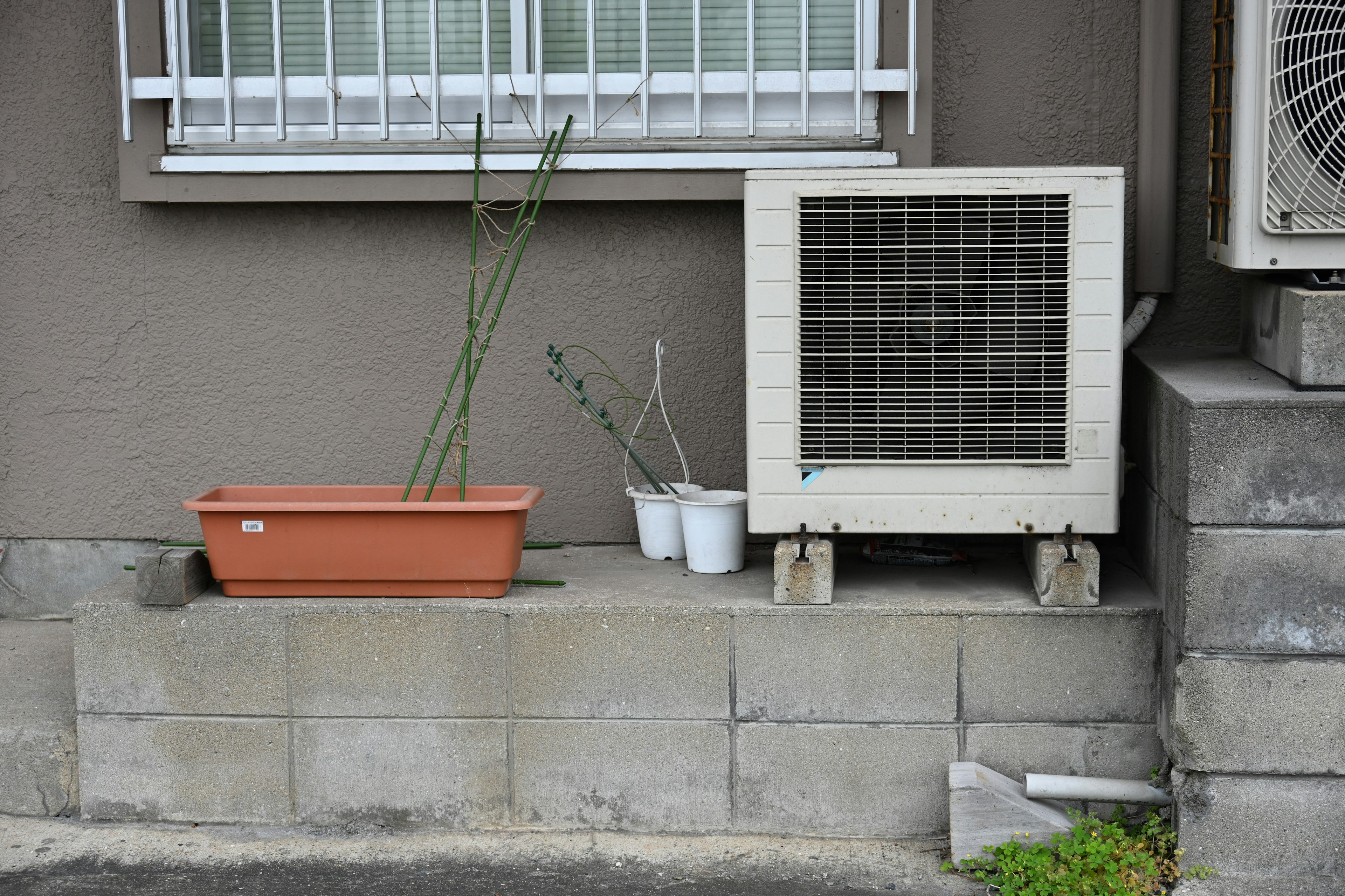 Vista esterna di una casa con un'unità di climatizzazione e un vaso di fiori