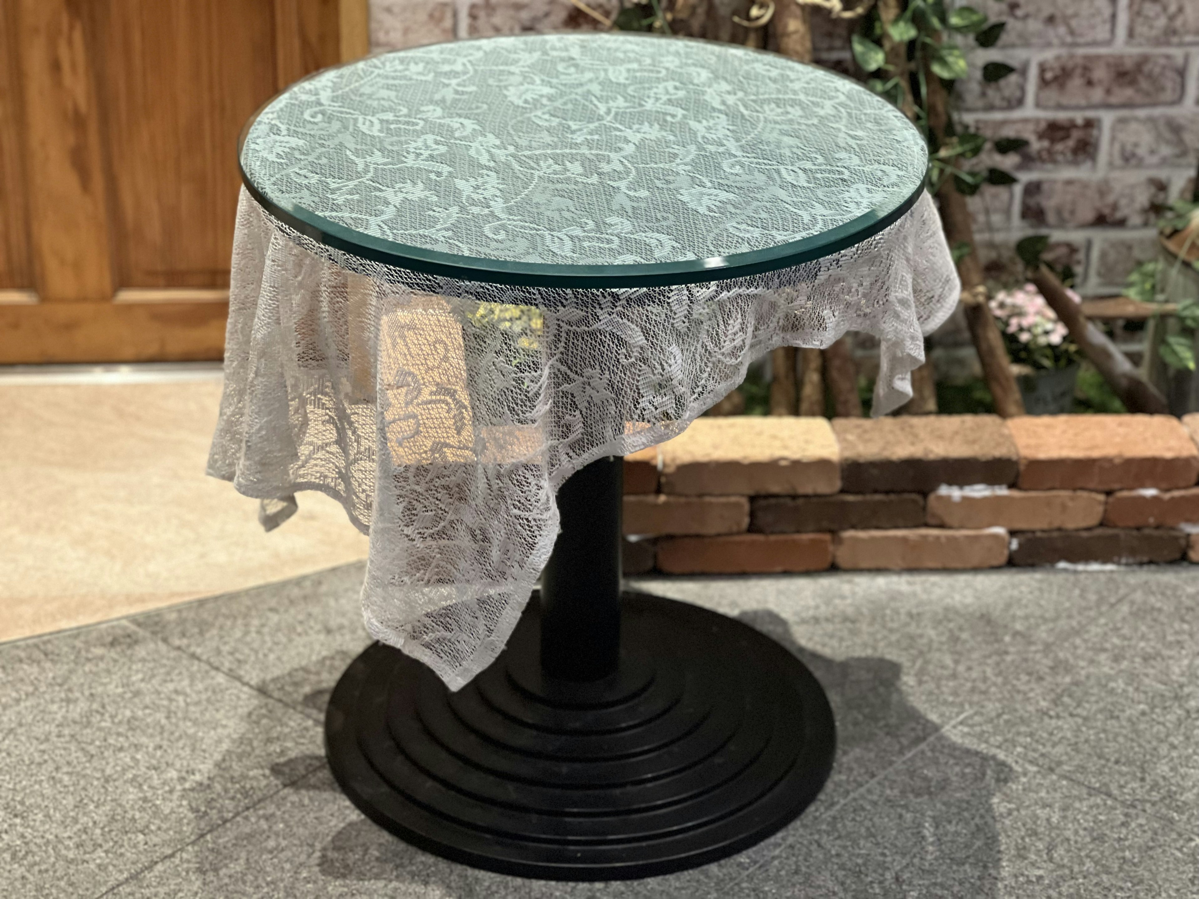 Table ronde en verre avec nappe en dentelle