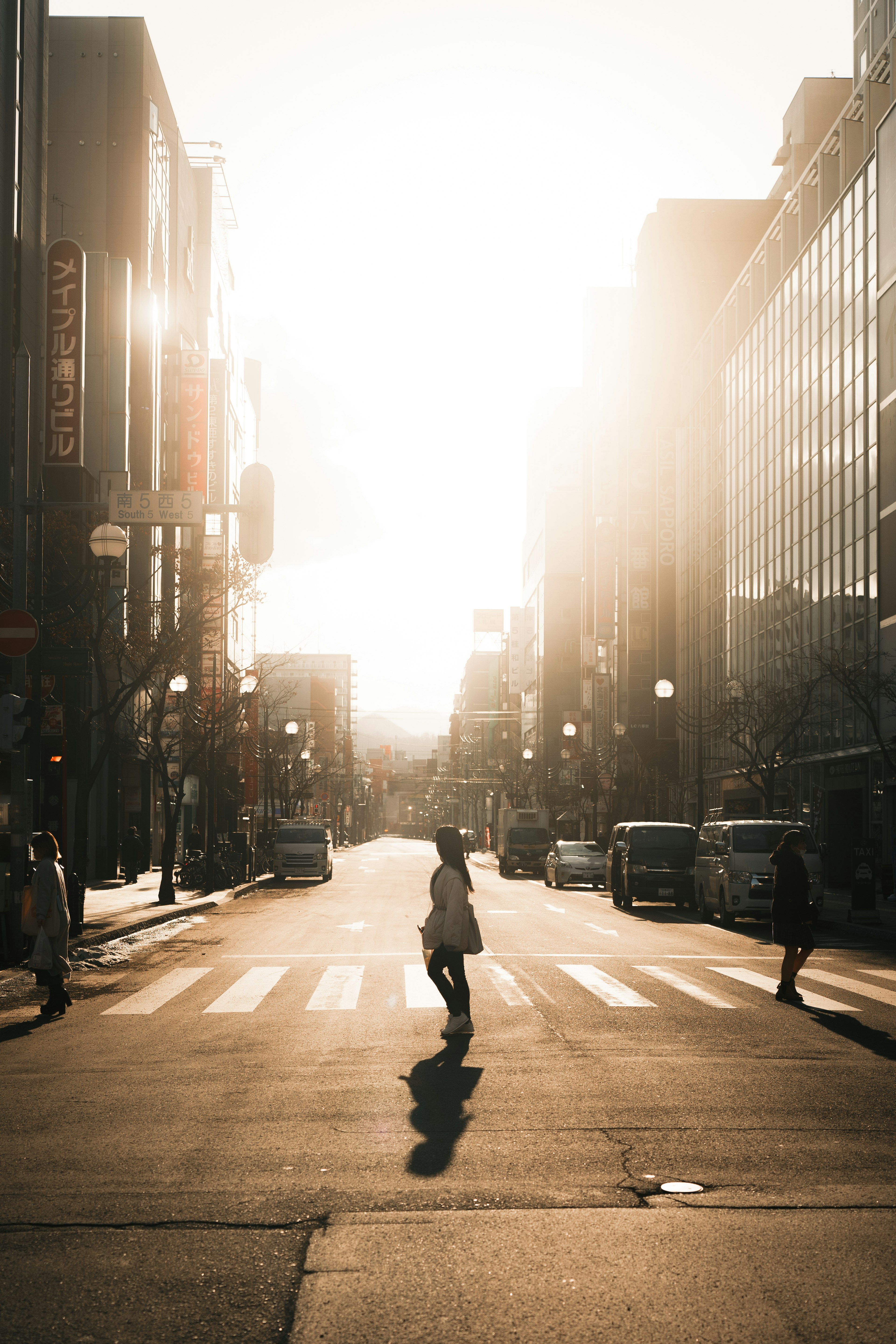 夕陽背景下穿越街道的人影和城市景觀