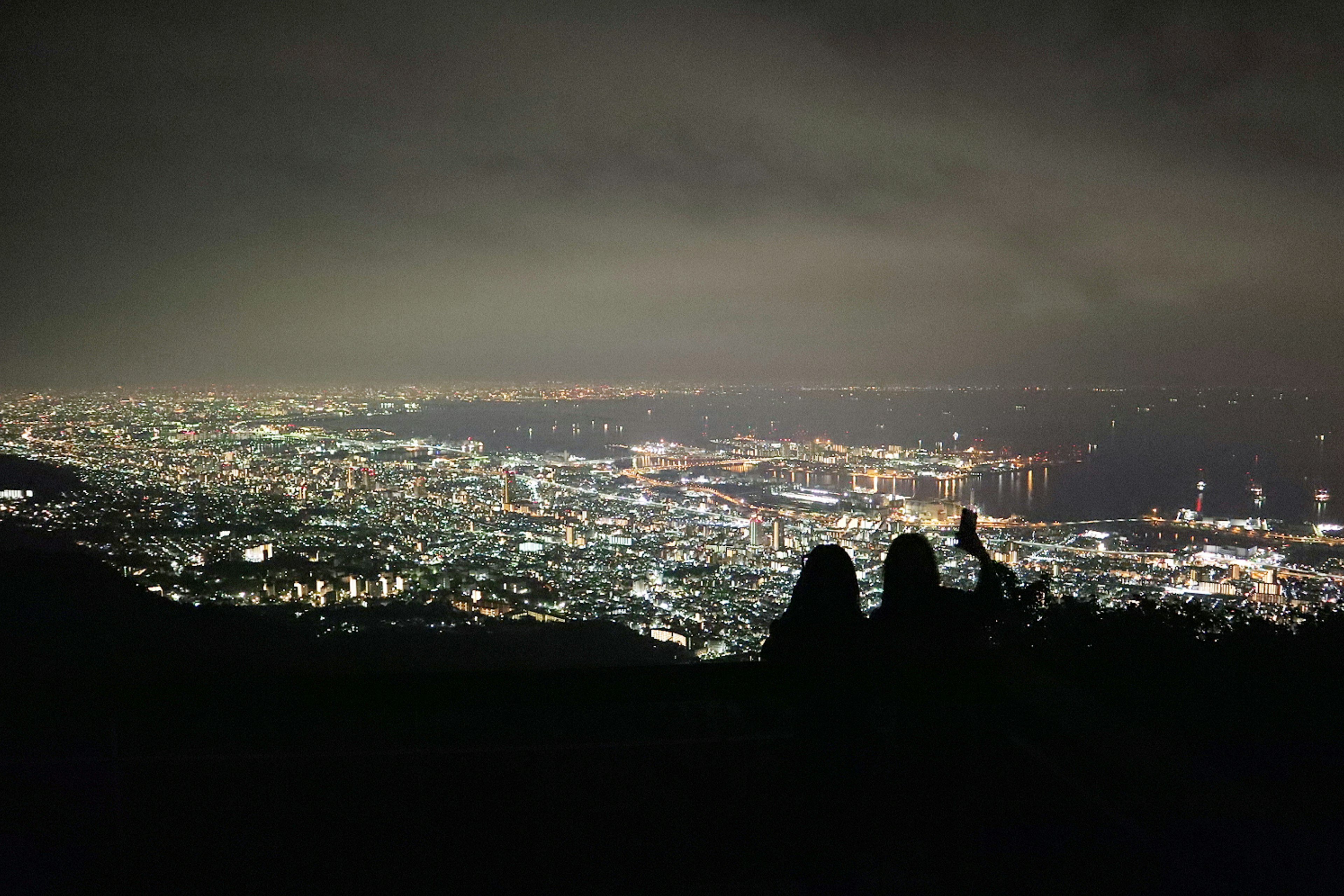 Schatten von zwei Personen, die auf eine nächtliche Stadtlandschaft blicken