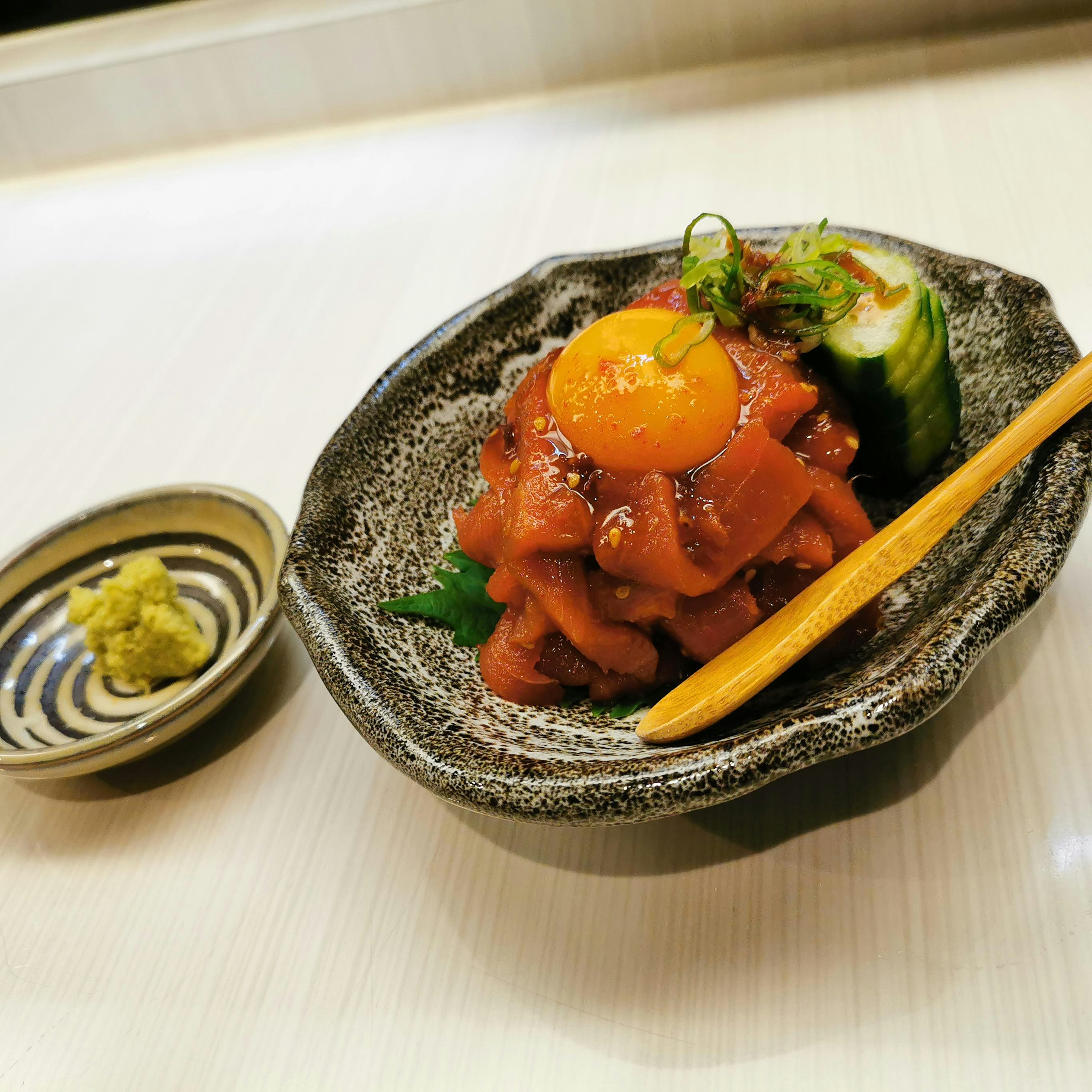 Dish featuring salmon sashimi topped with an egg yolk