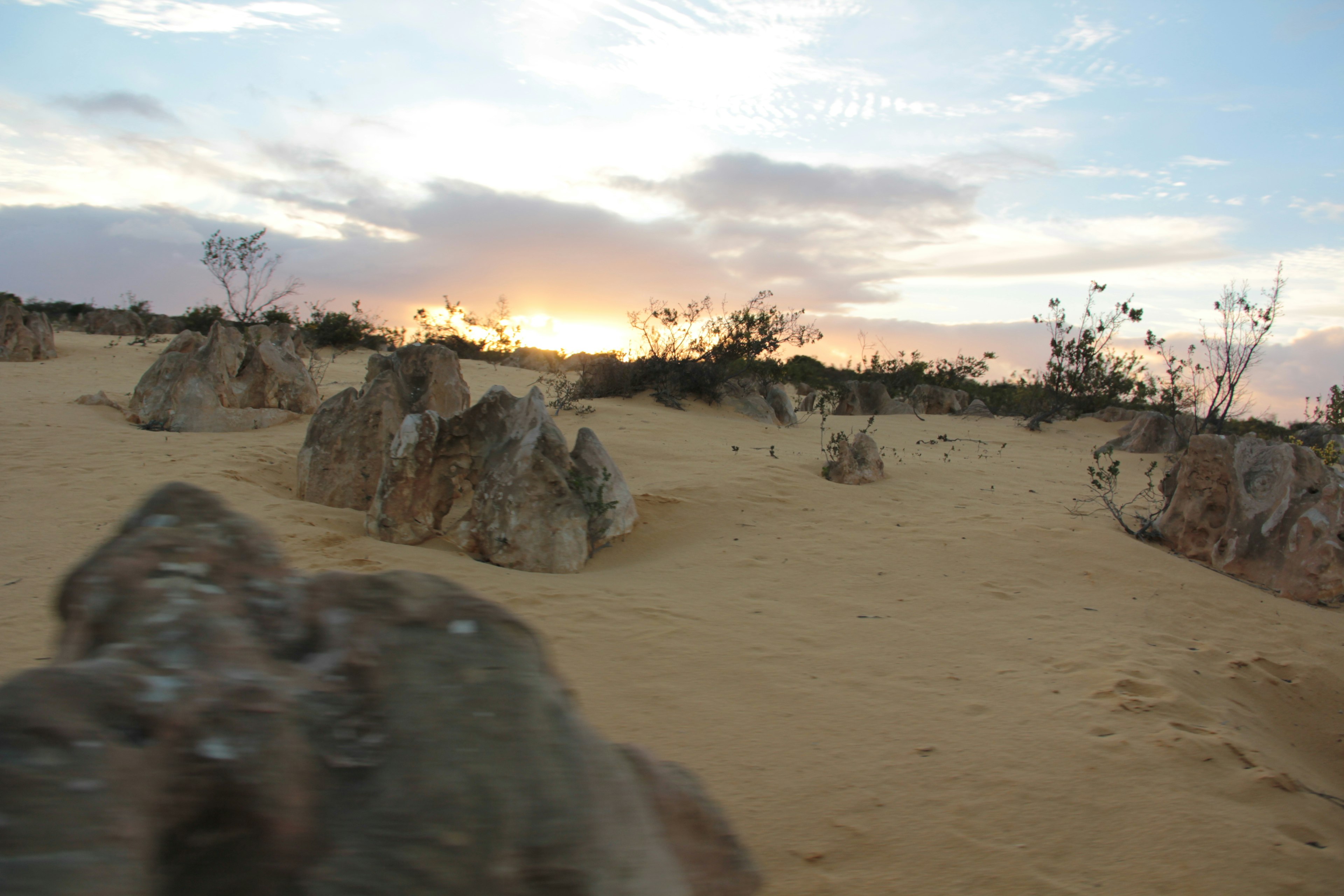 Paysage avec des dunes de sable et des rochers au coucher du soleil