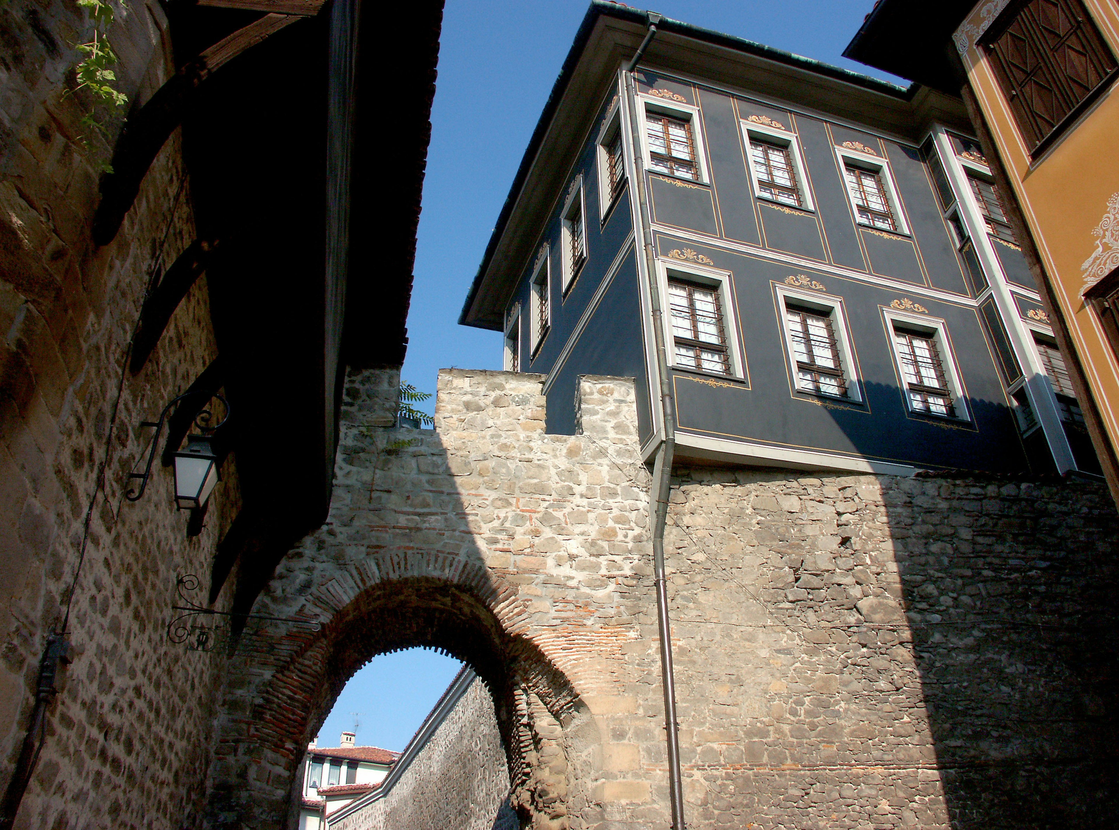 Historic stone archway alongside modern building in urban setting