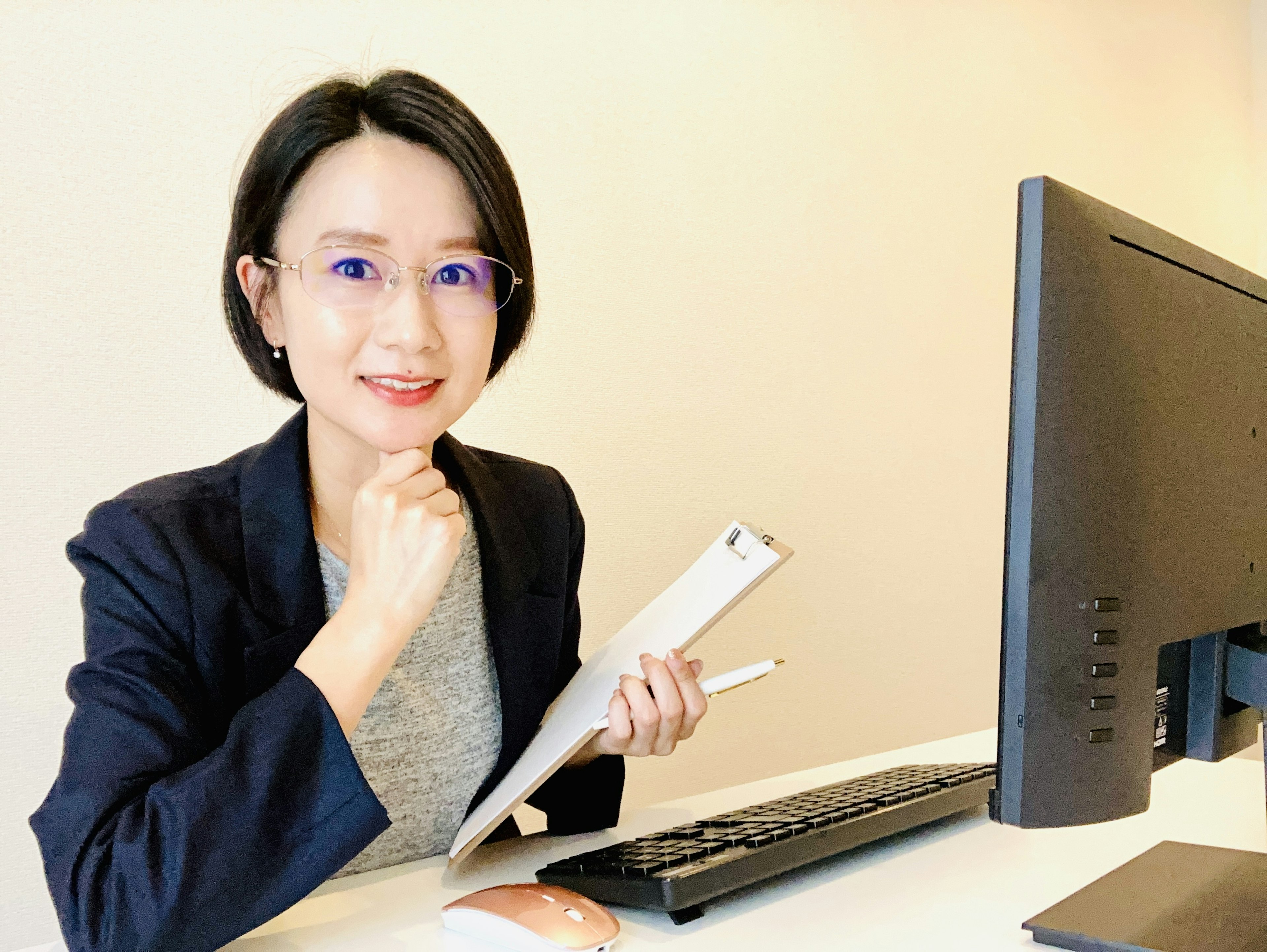 Femme souriante assise à un bureau tenant un stylo et des documents