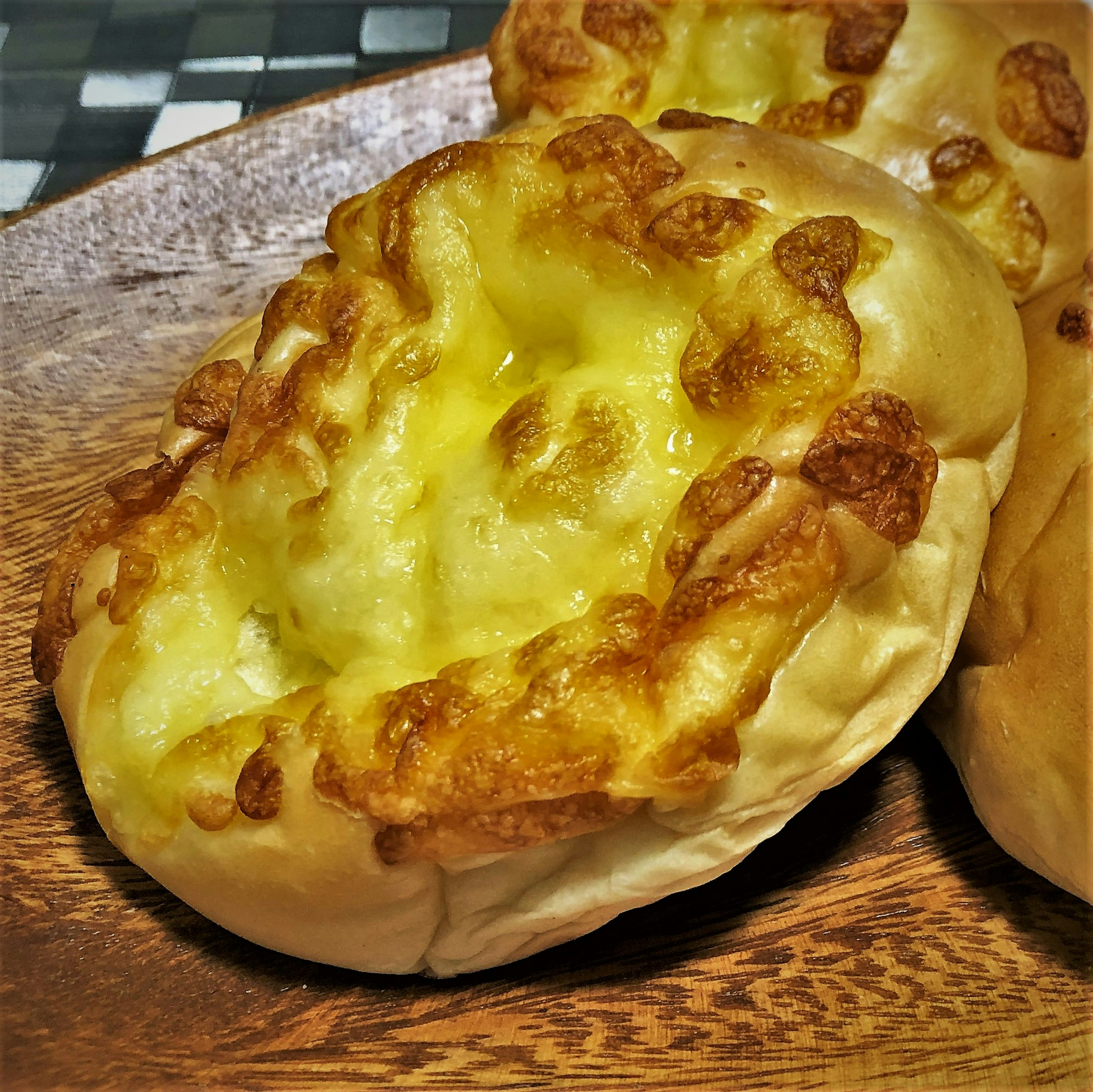 Freshly baked cheese bread displayed on a wooden plate