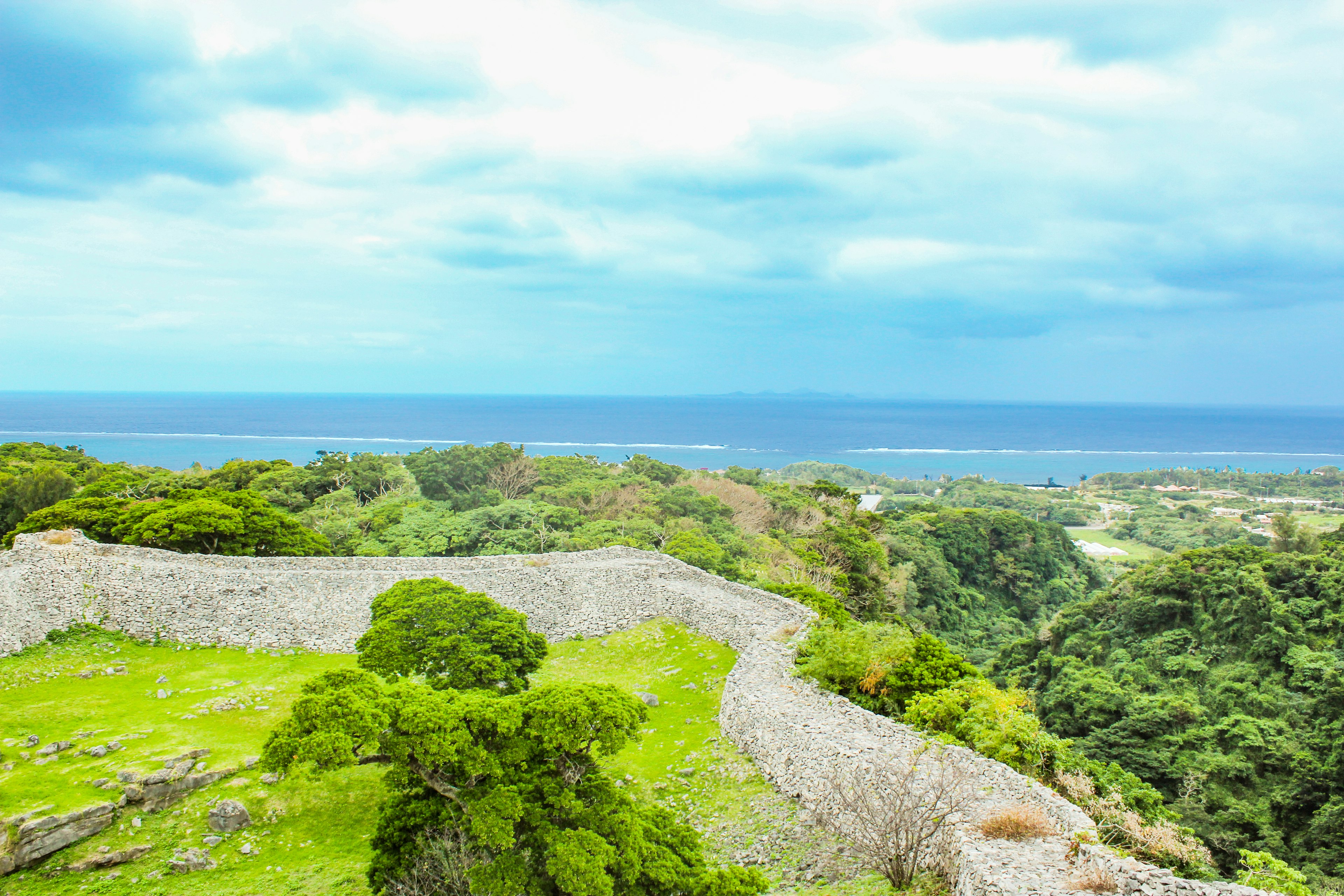 Ancient castle ruins with a backdrop of blue ocean and green hills