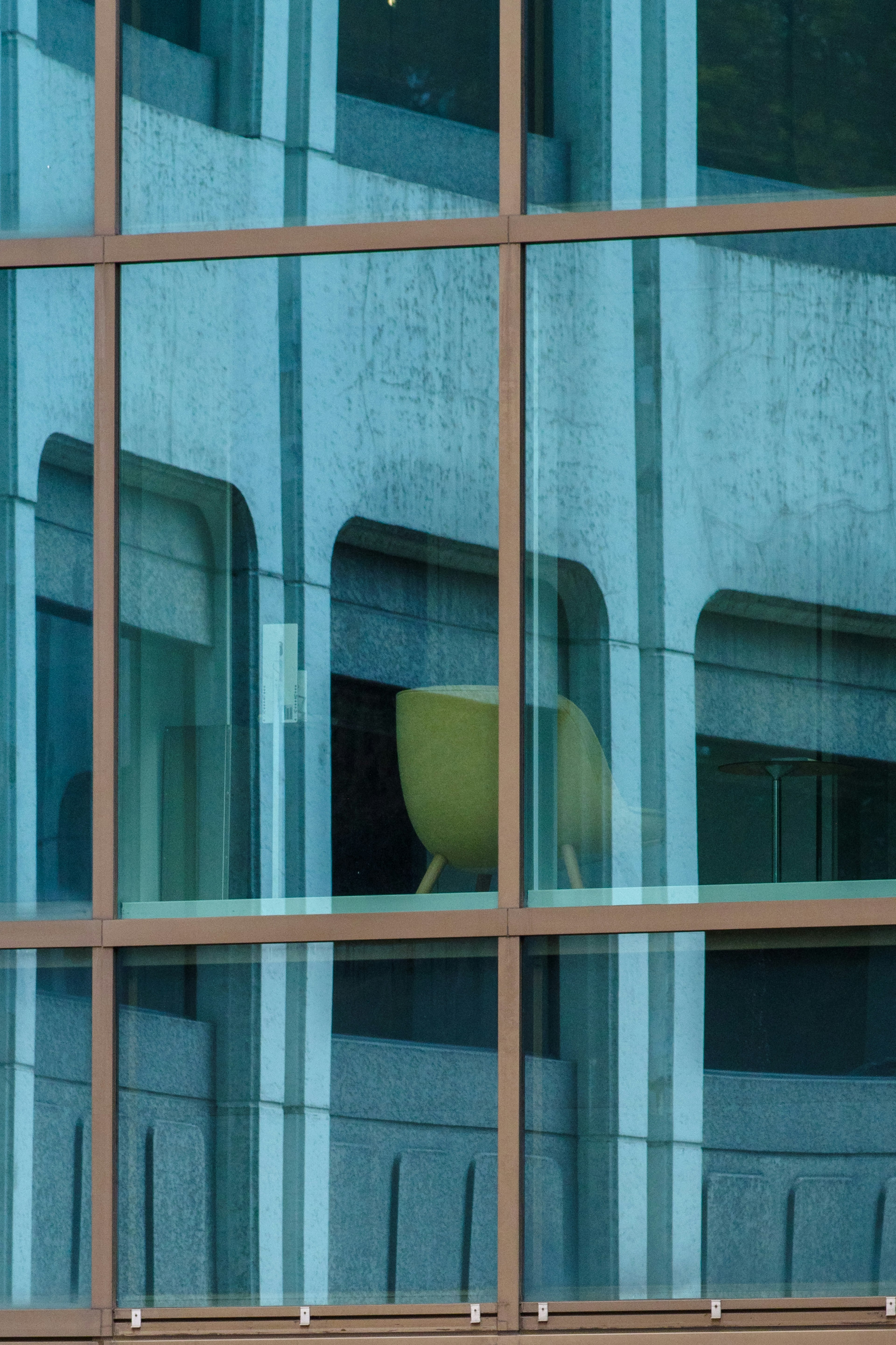 Reflejo de una silla amarilla en ventanas de vidrio azul