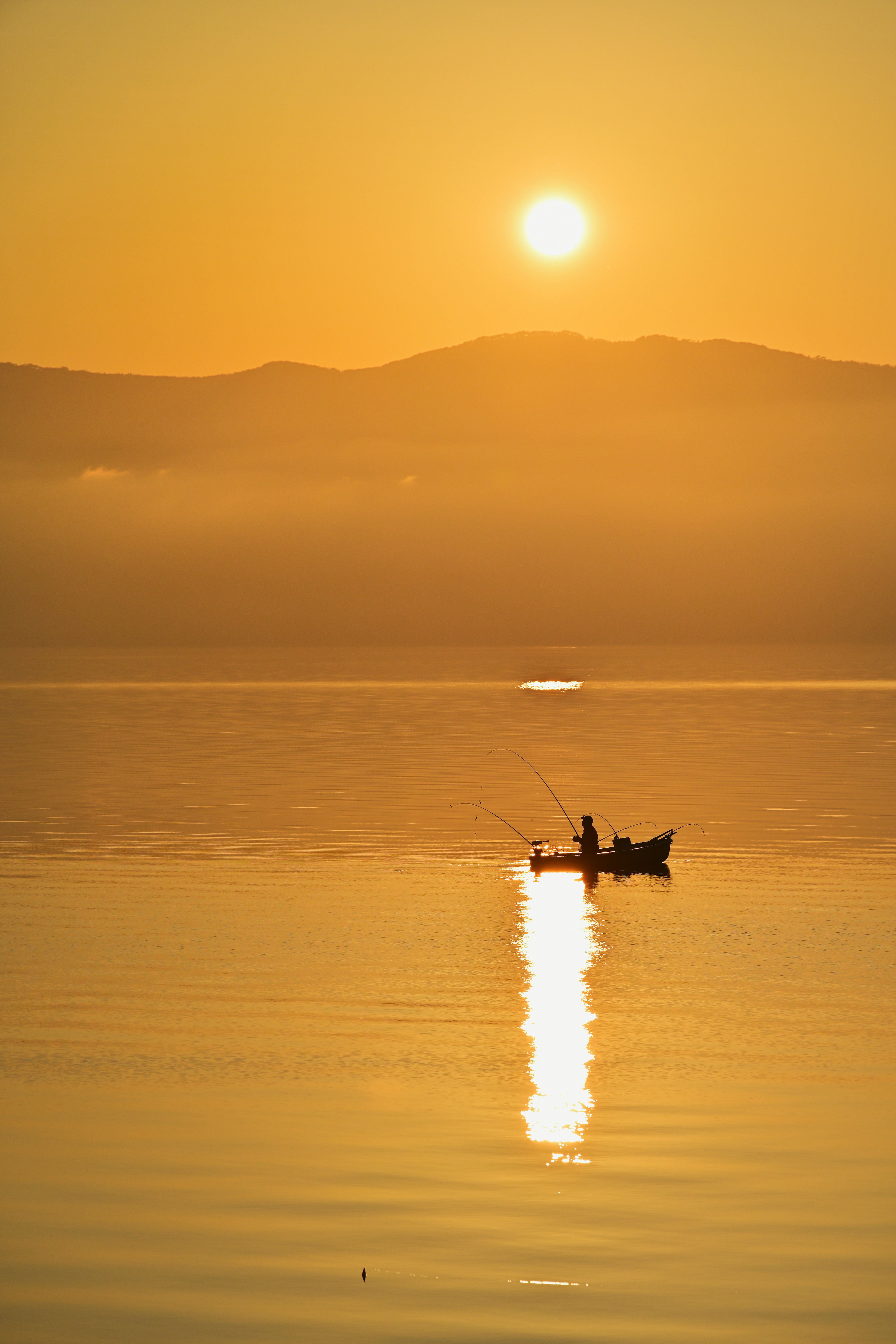 Una escena de lago tranquila con un pequeño bote flotando bajo un atardecer que se refleja en el agua