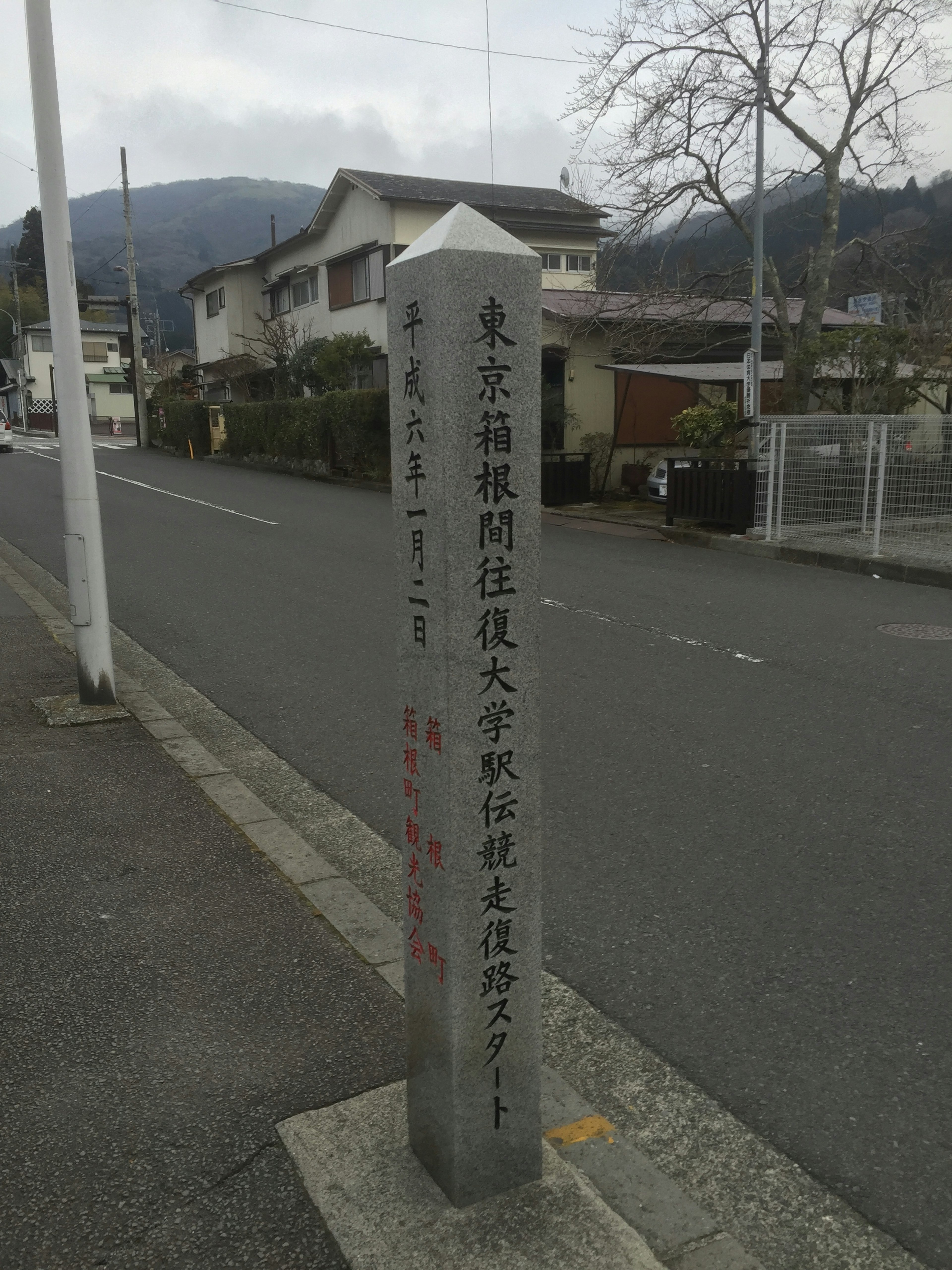 街道の案内標識が立っている風景 周囲には住宅と山々が見える