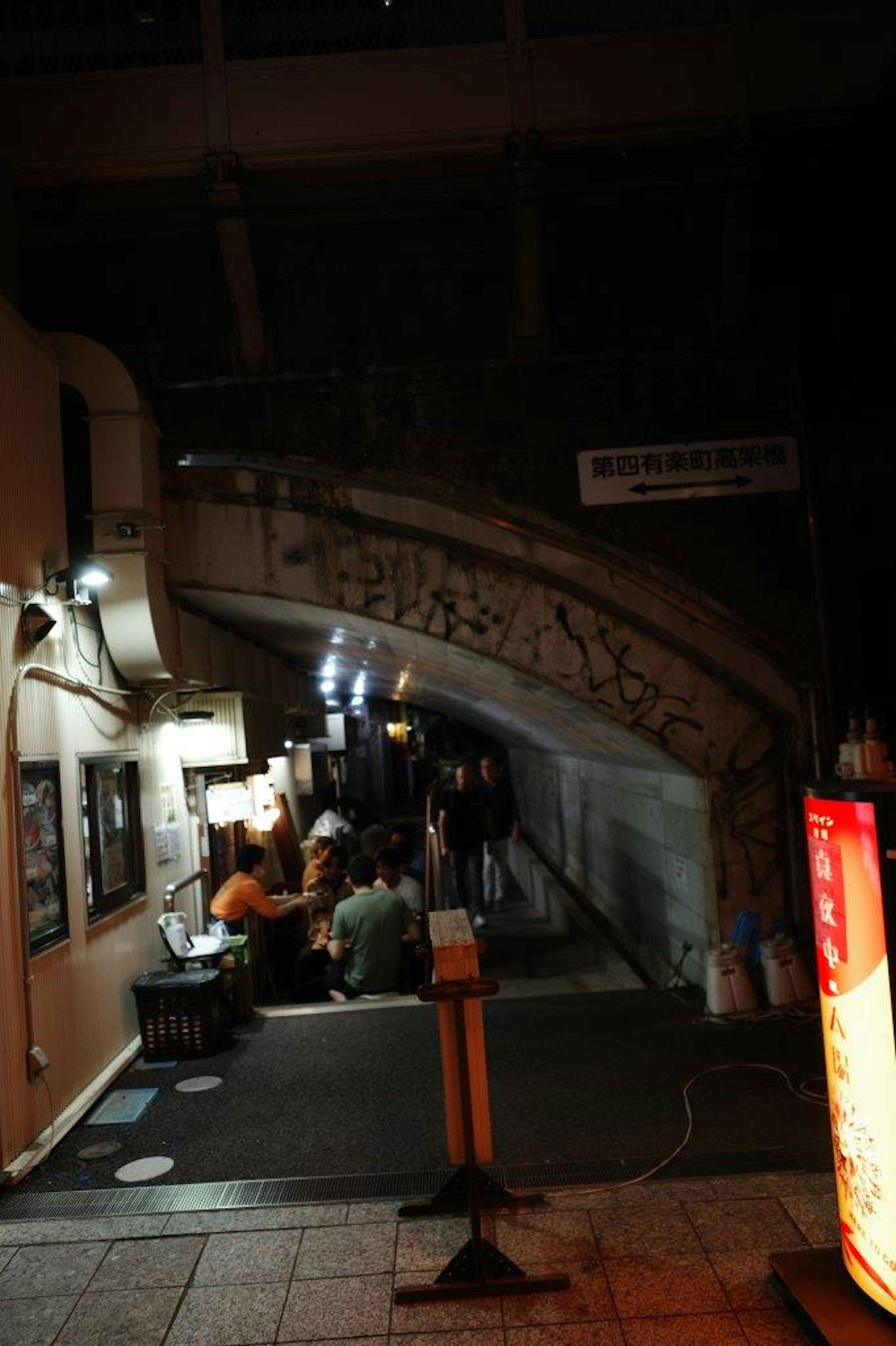 Rassemblement de personnes sous un pont avec éclairage ambiant