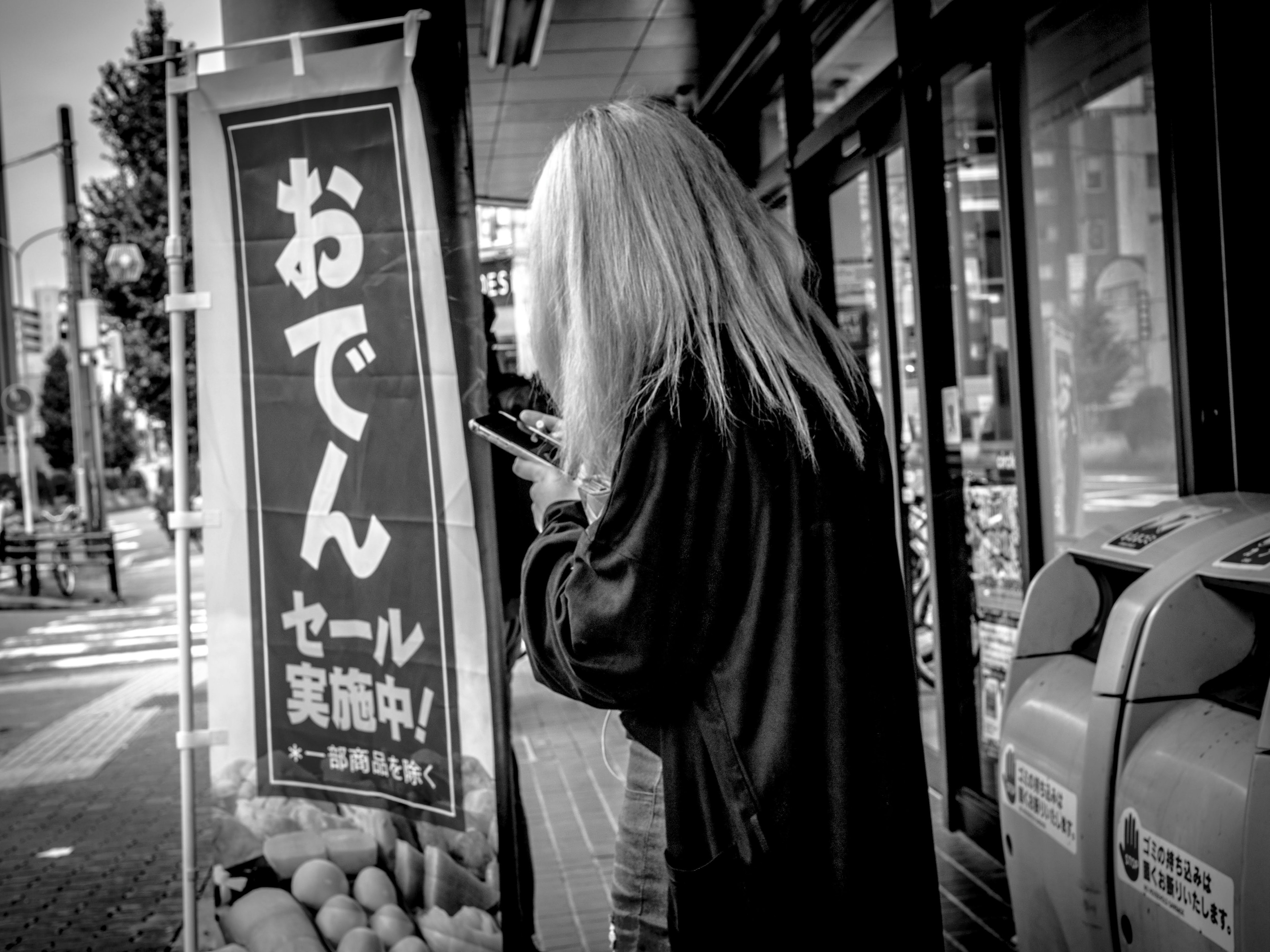 A woman with long hair looking at an oden sign in black and white