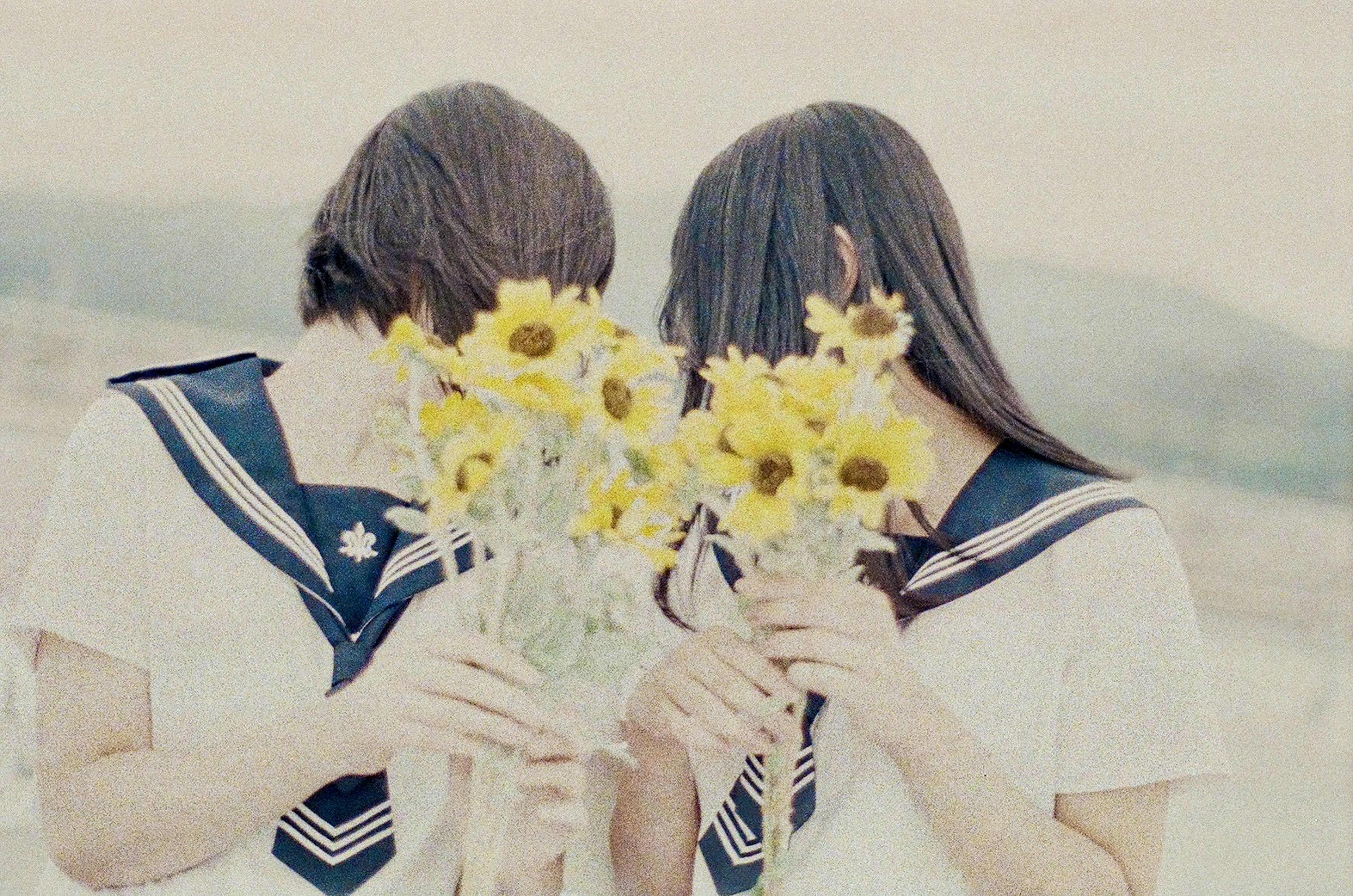 Two students holding sunflower bouquets