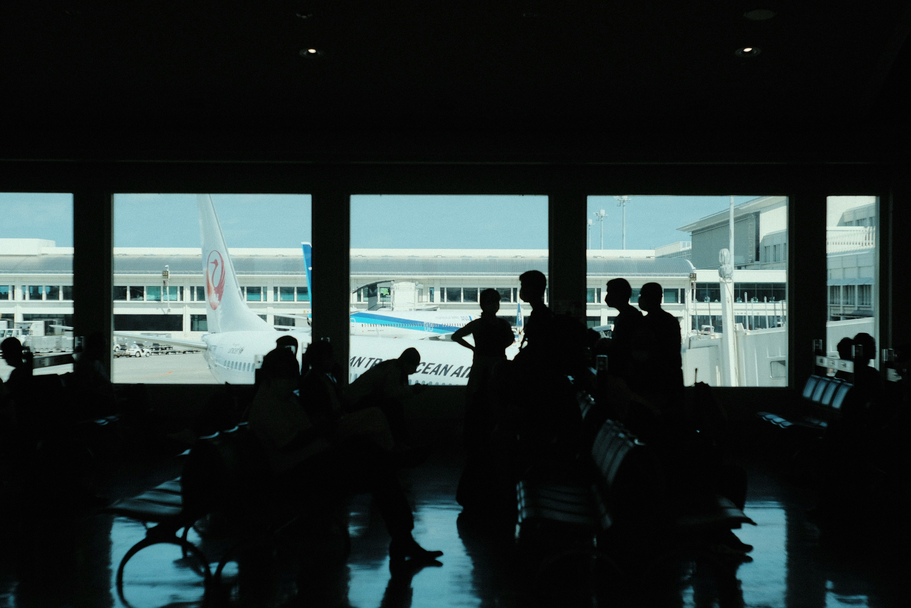 Silhouettes de personnes dans un terminal d'aéroport avec vue sur un avion