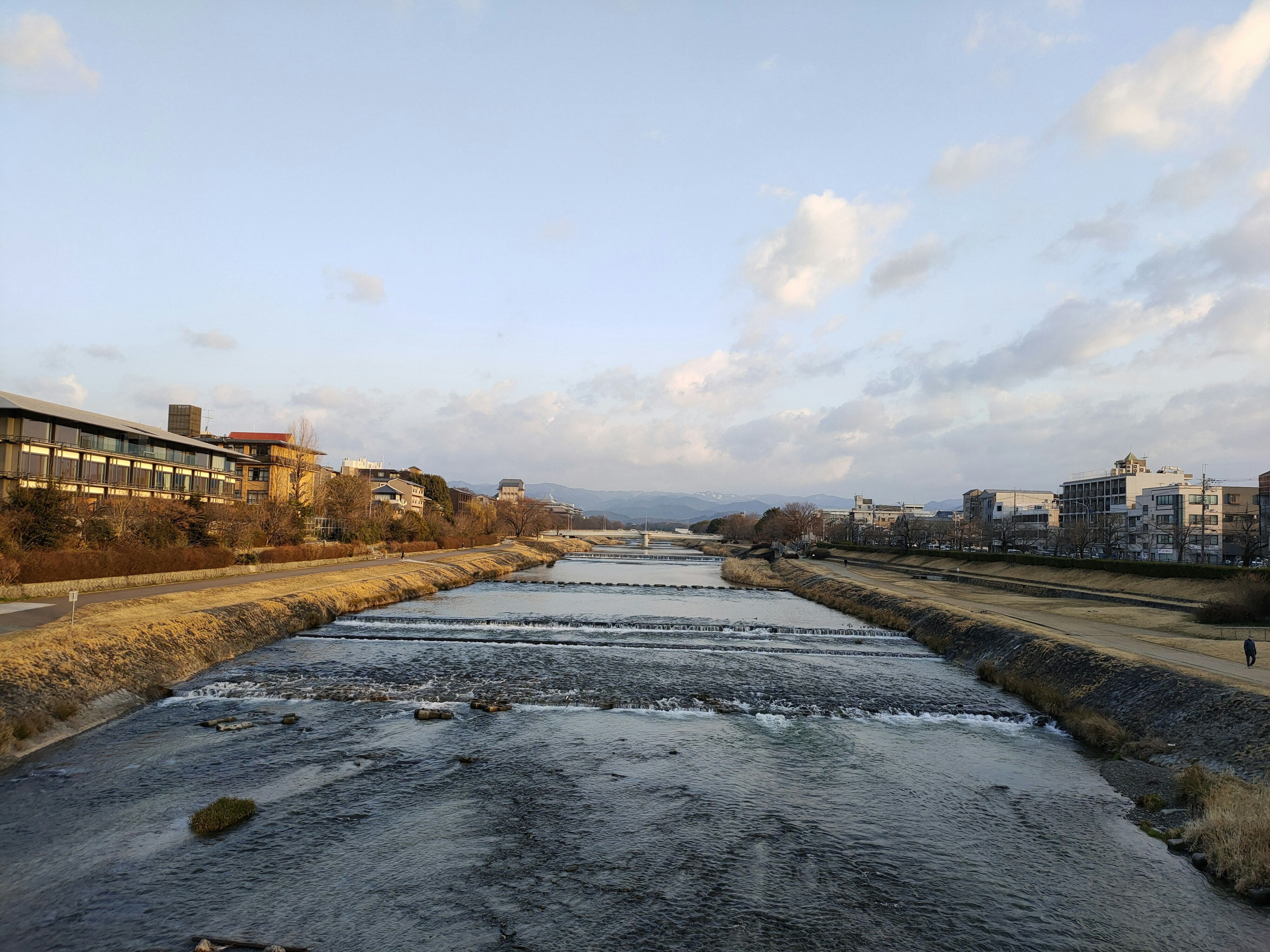 Vista serena del fiume con edifici circostanti e cielo nuvoloso