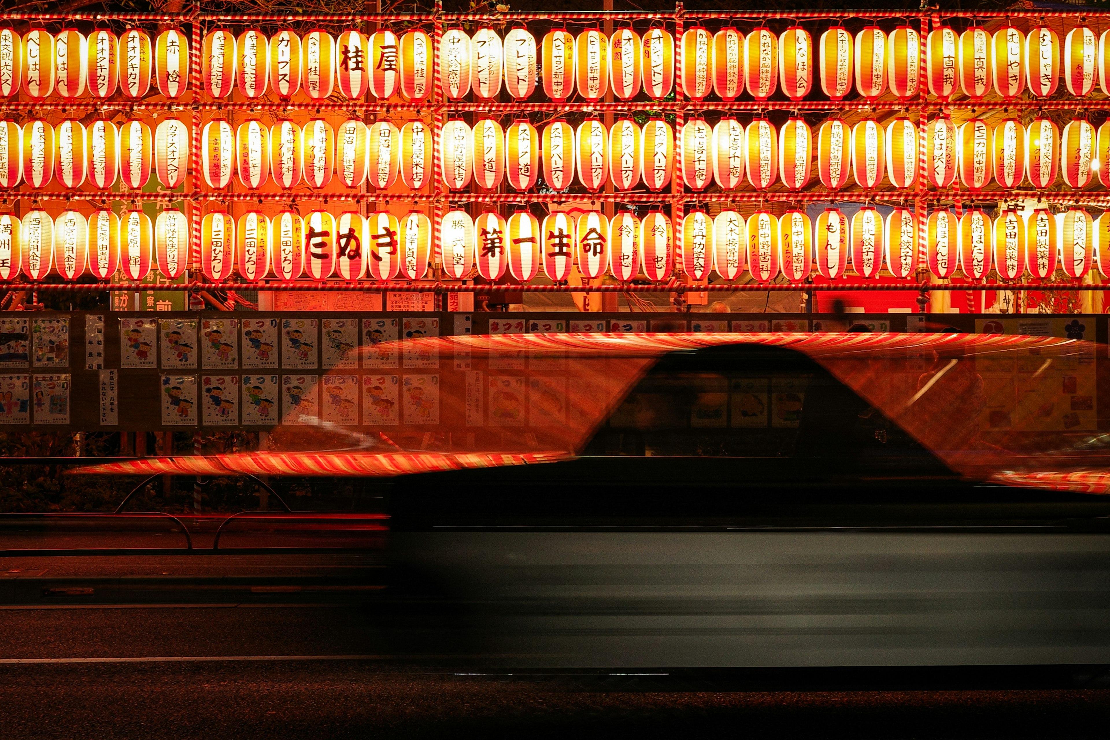 Silhouette di un'auto in movimento contro uno sfondo di lanterne rosse