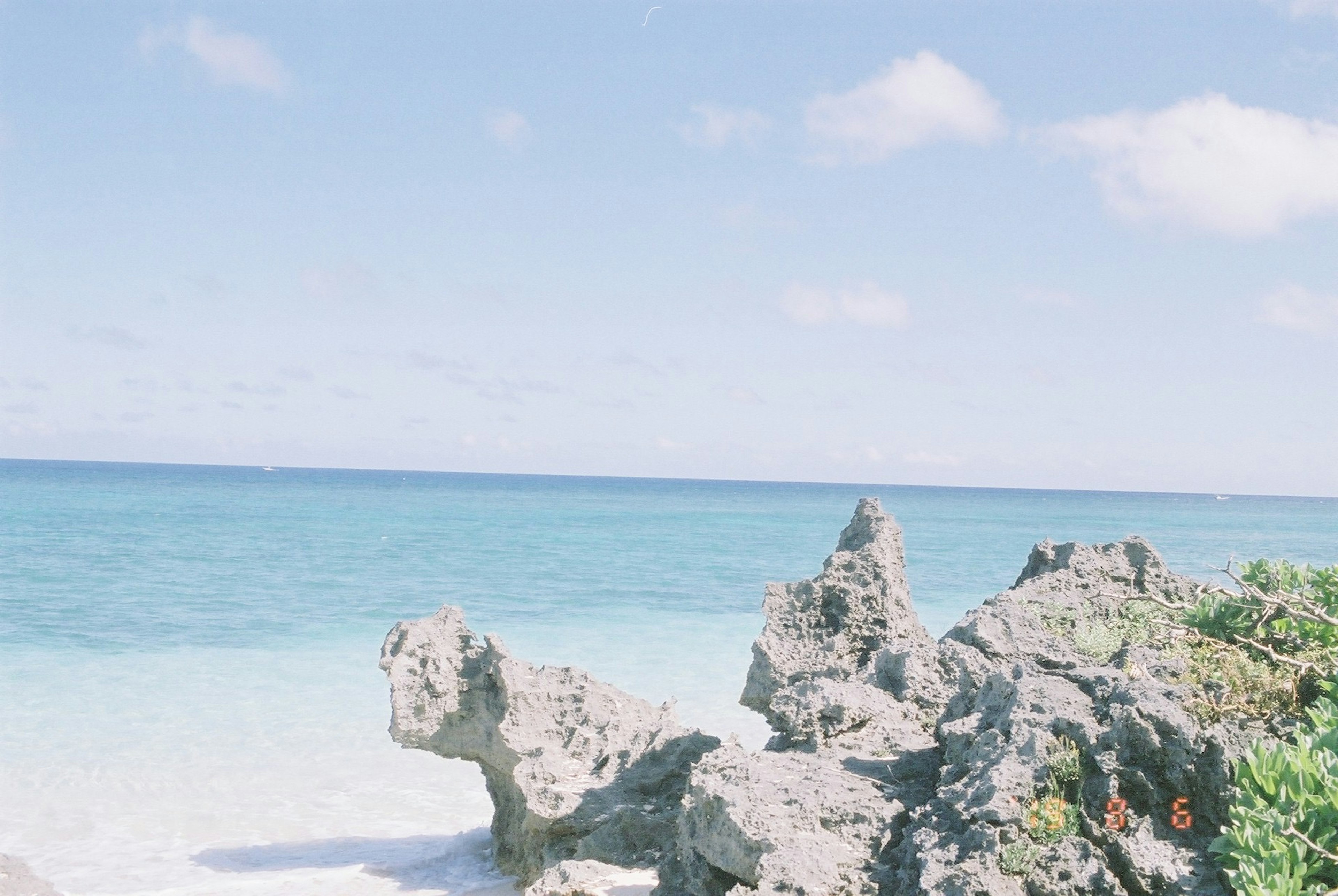 Rocky shoreline with clear blue ocean and white sandy beach